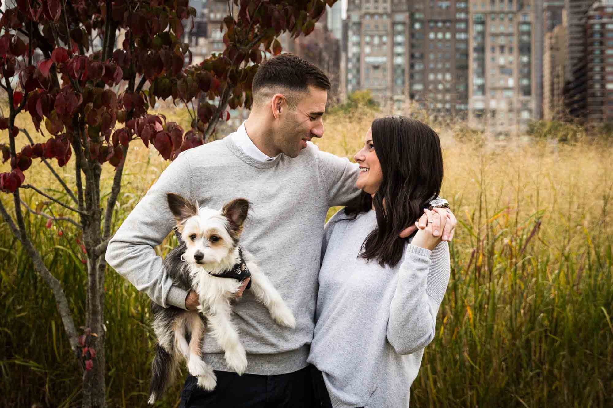 Couple hugging and holding dog for an article on pet engagement photo tips
