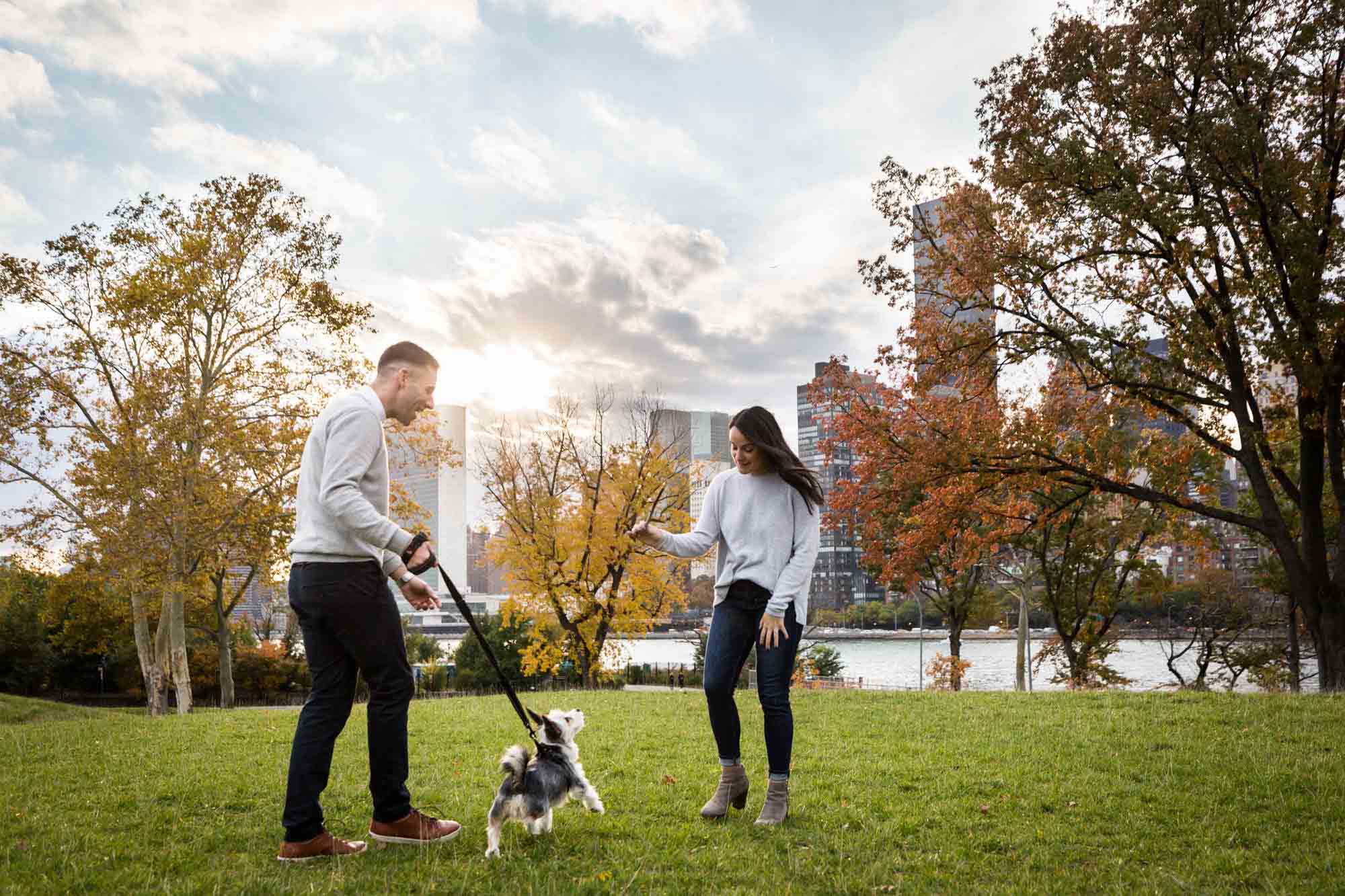Couple playing with dog during Roosevelt Island engagement photo shoot for an article on pet engagement photo tips