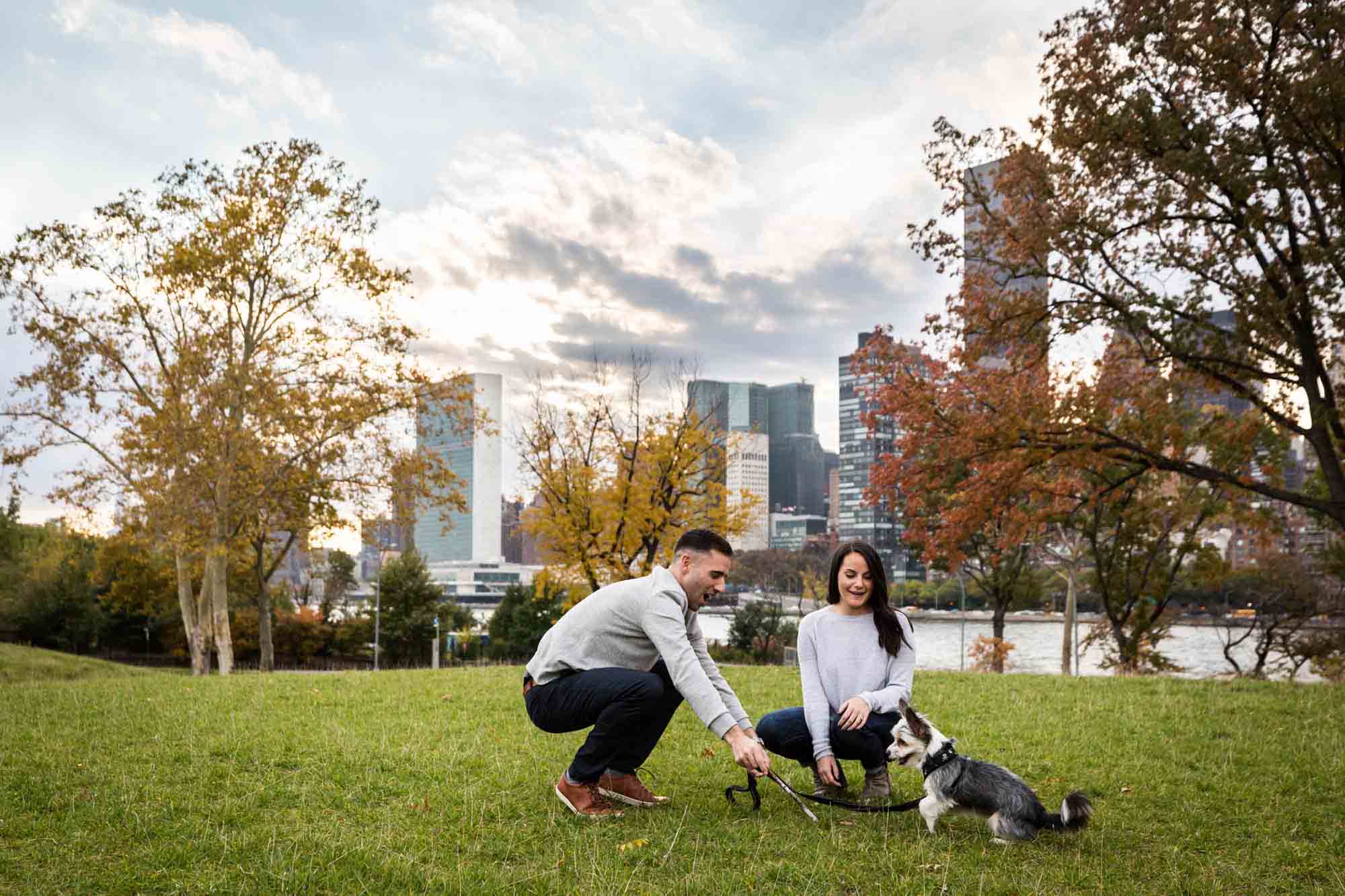 Couple playing with dog on grass for an article on pet engagement photo tips