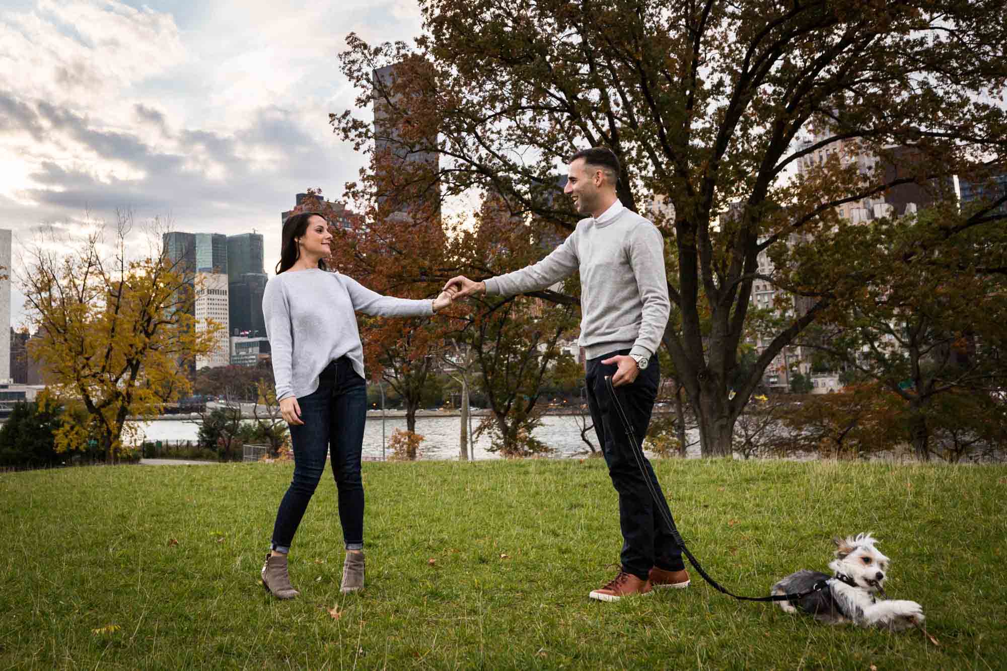 Couple holding hands with dog on leash for an article on pet engagement photo tips