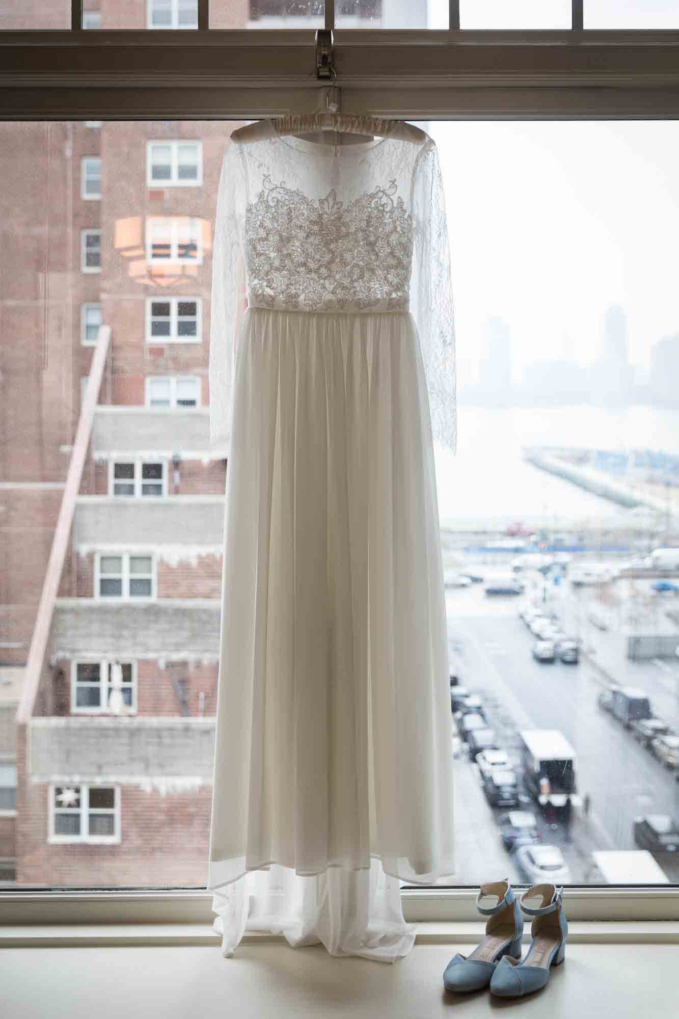 Wedding dress hanging in front of a window