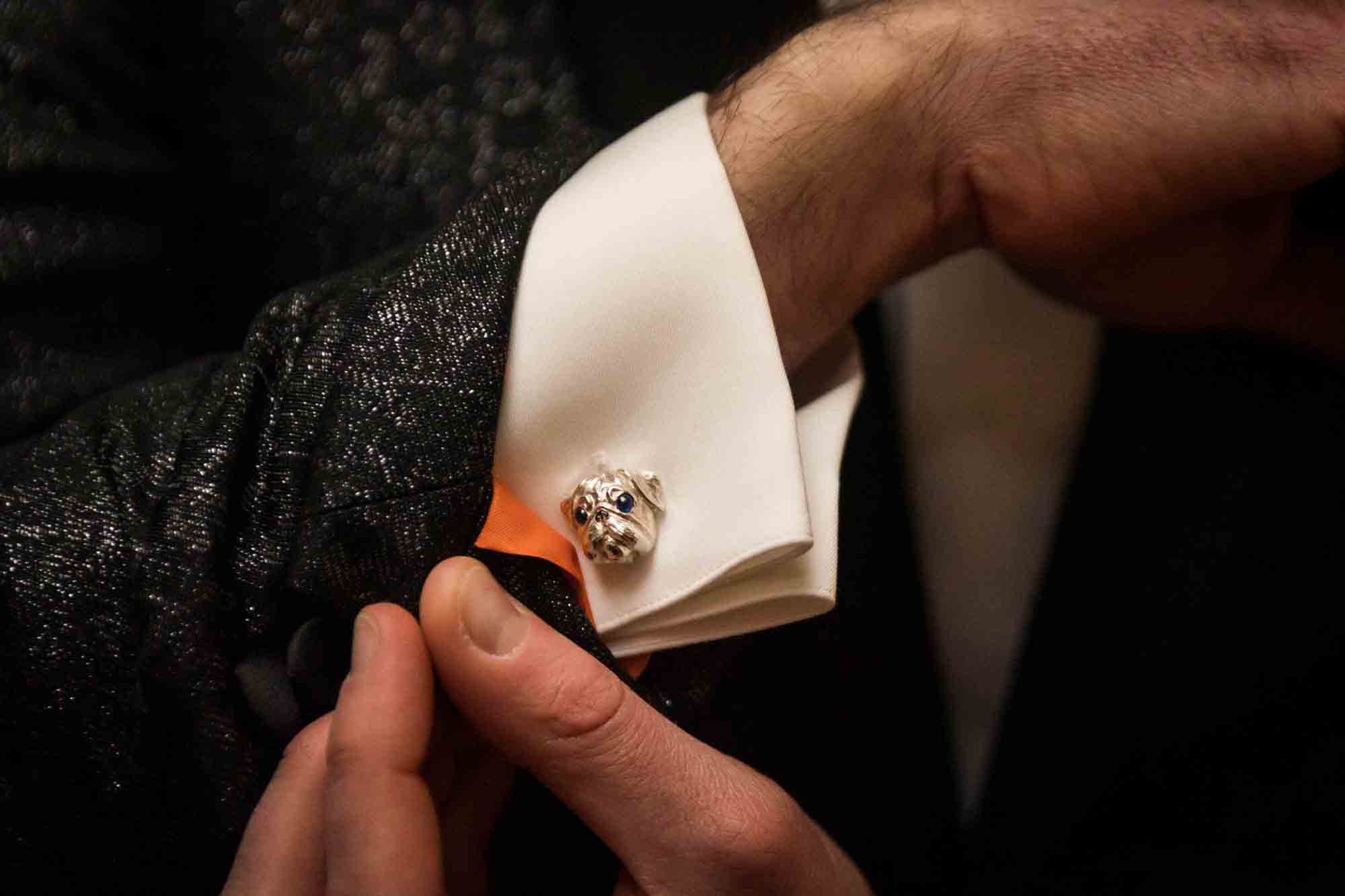 Man showing silver cufflink in the shape of a bulldog