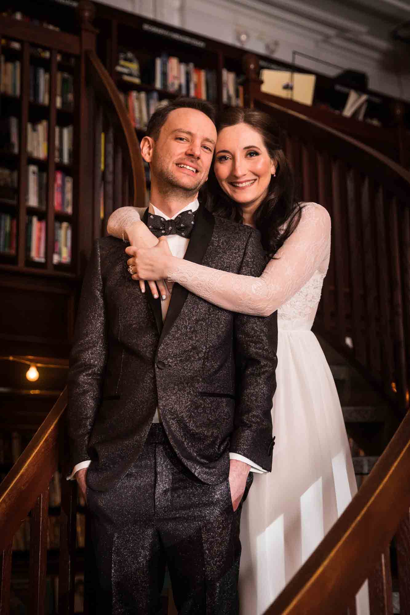 Bride and groom hugging on staircase at a Housing Works Bookstore wedding