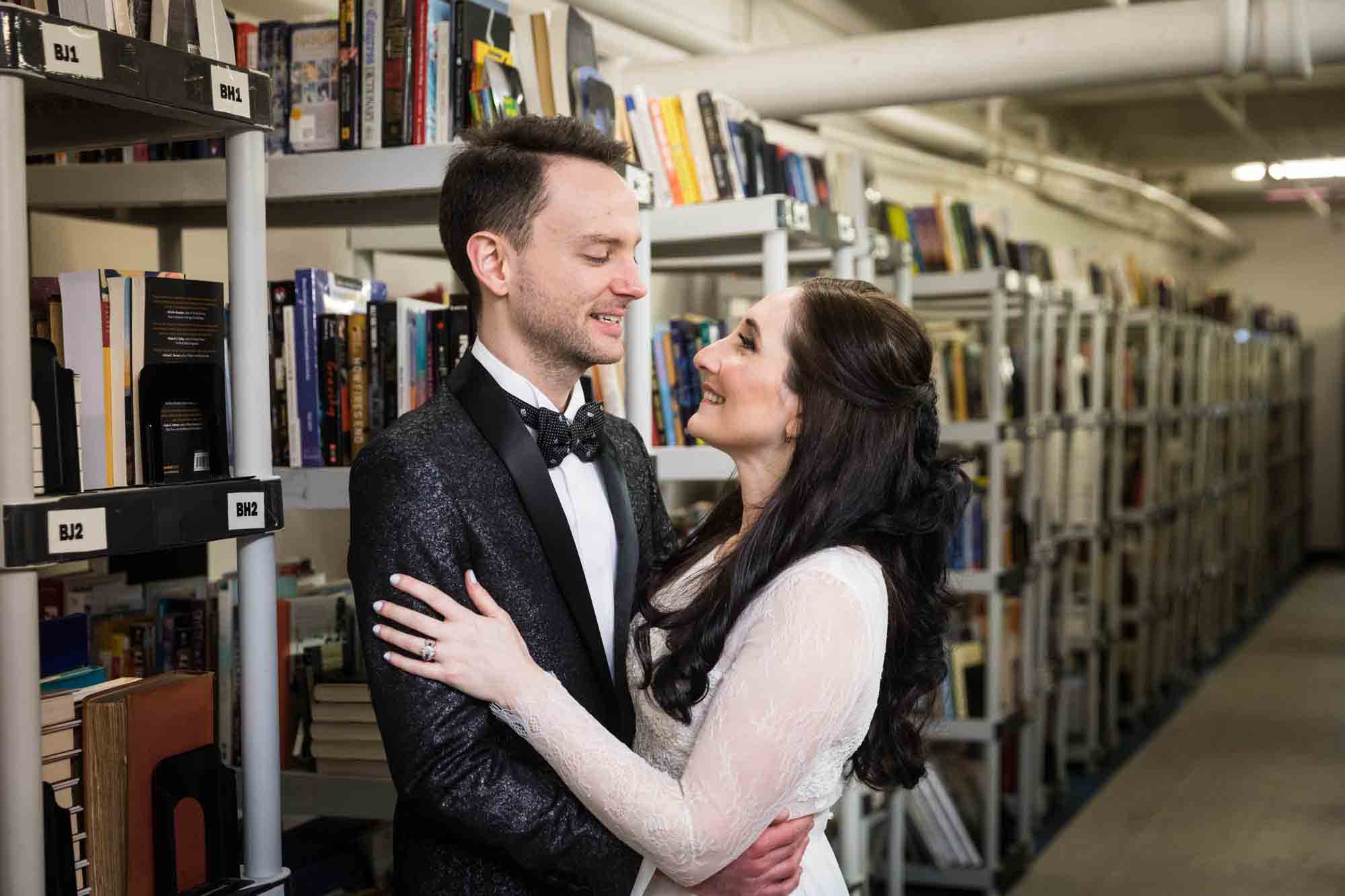 Bride and groom hugging in front of bookcases at a Housing Works Bookstore wedding