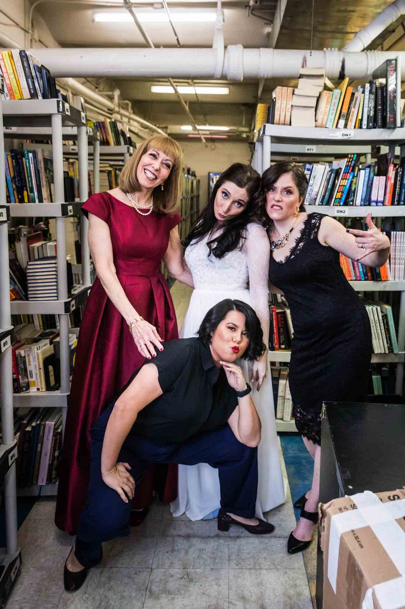Bridal party in funny pose in front of bookcase at a Housing Works Bookstore wedding