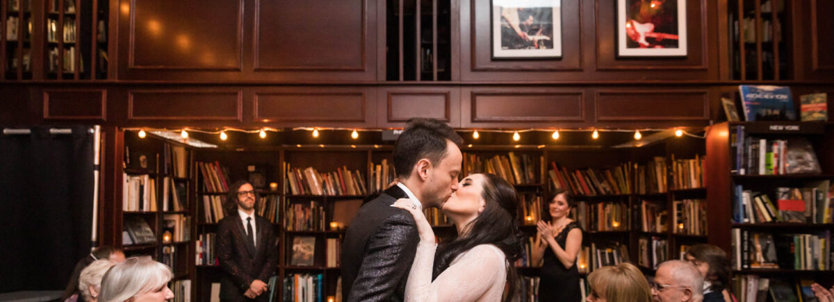 Bride and groom kissing in bookstore for an article on wedding ceremony photo tips