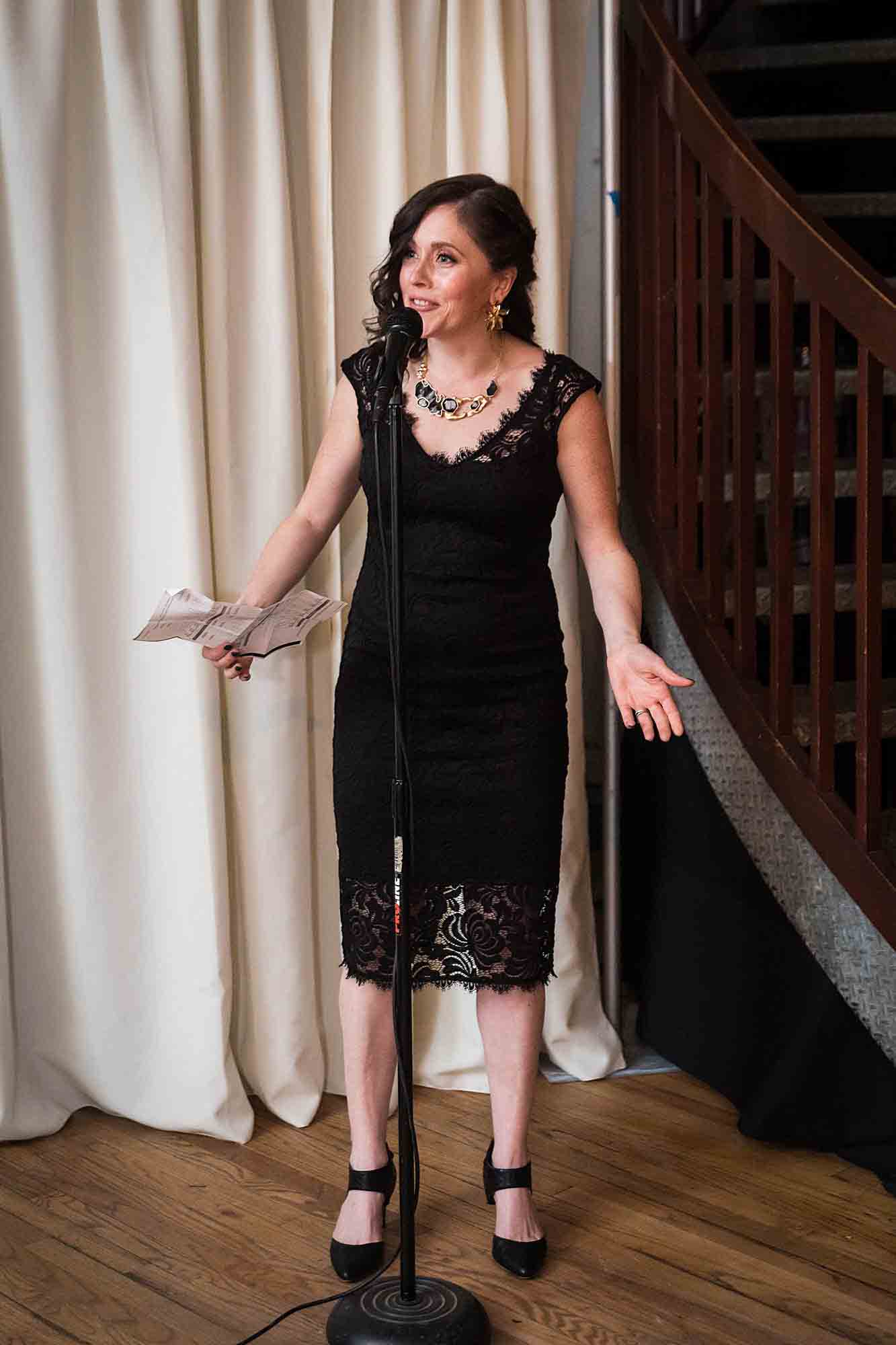 Maid of honor in black dress speaking into microphone at a Housing Works Bookstore wedding