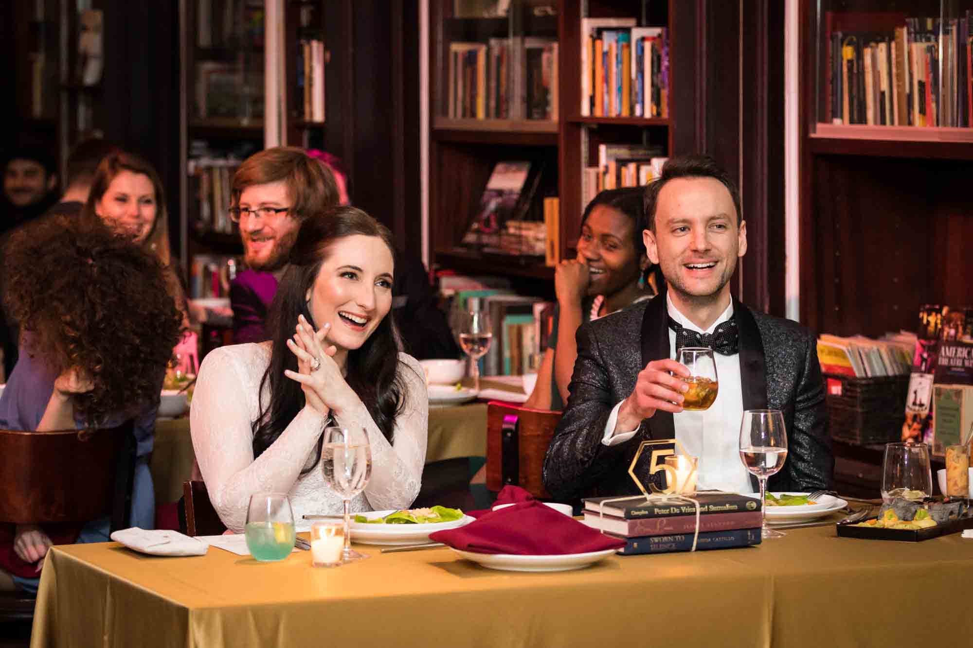 Bride and groom seated at a table smiling at a Housing Works Bookstore wedding