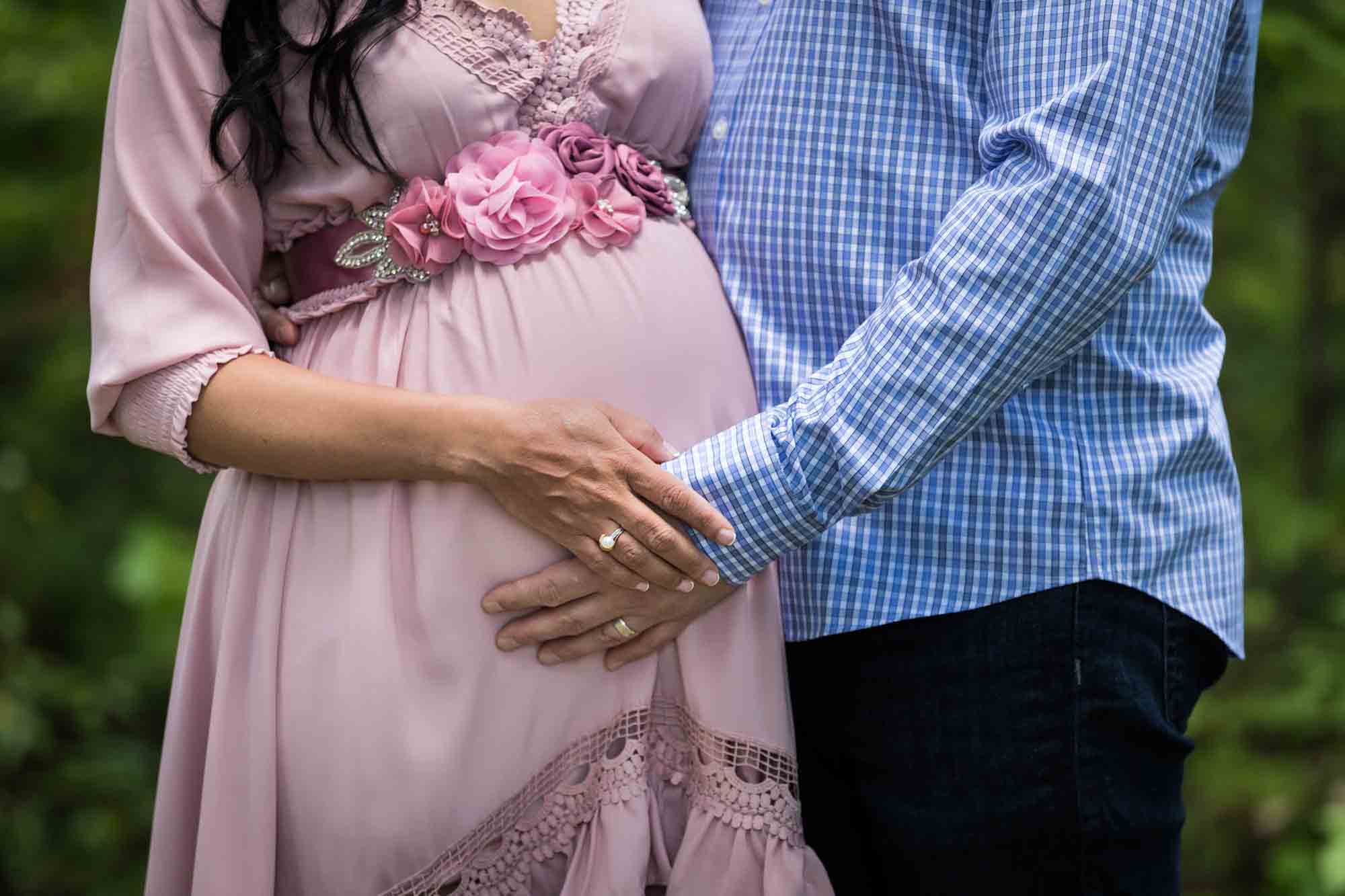 Close up of couple with hands on pregnant woman's stomach