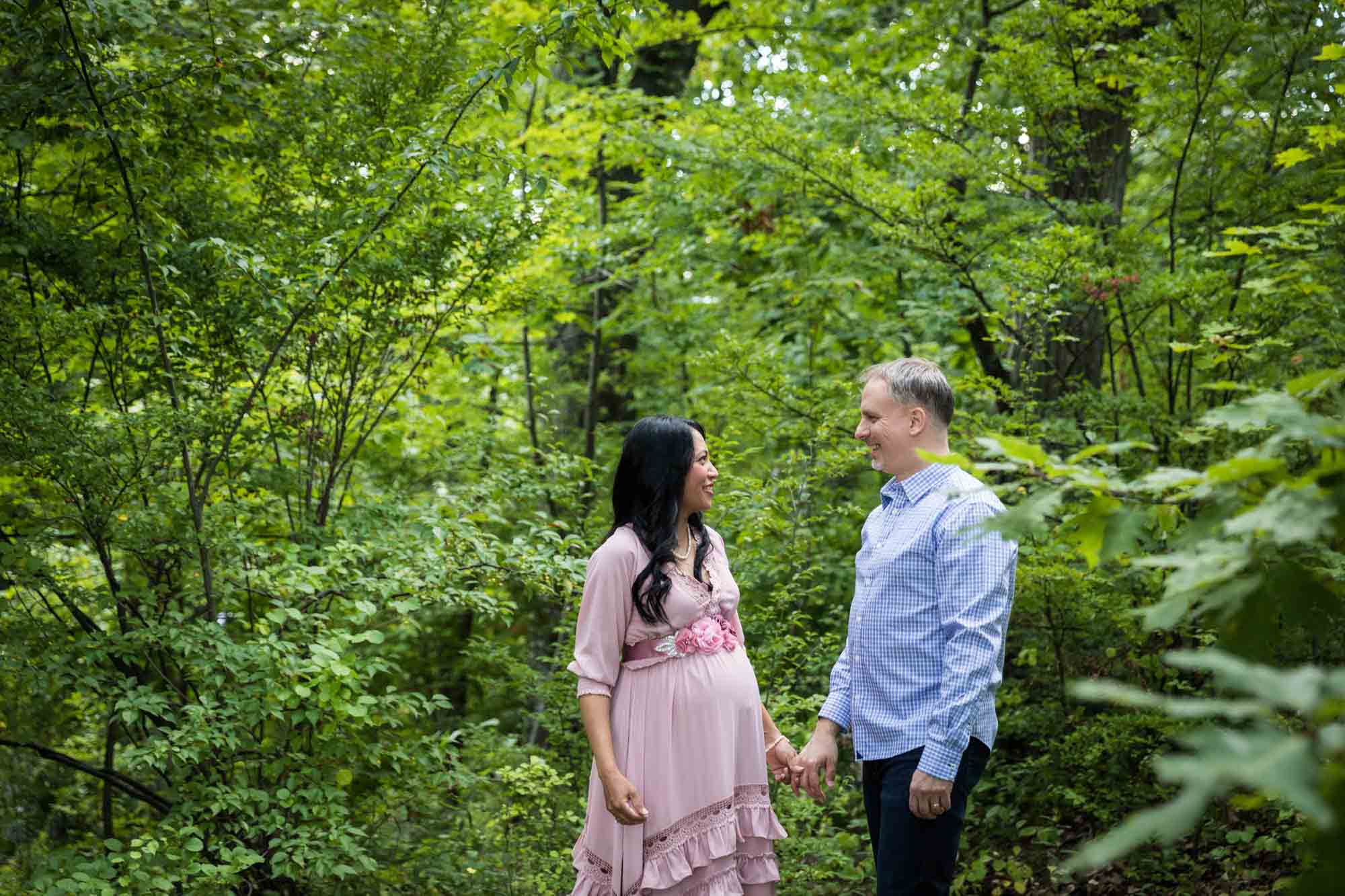 Forest Park maternity photos of a couple look at each other in a forest