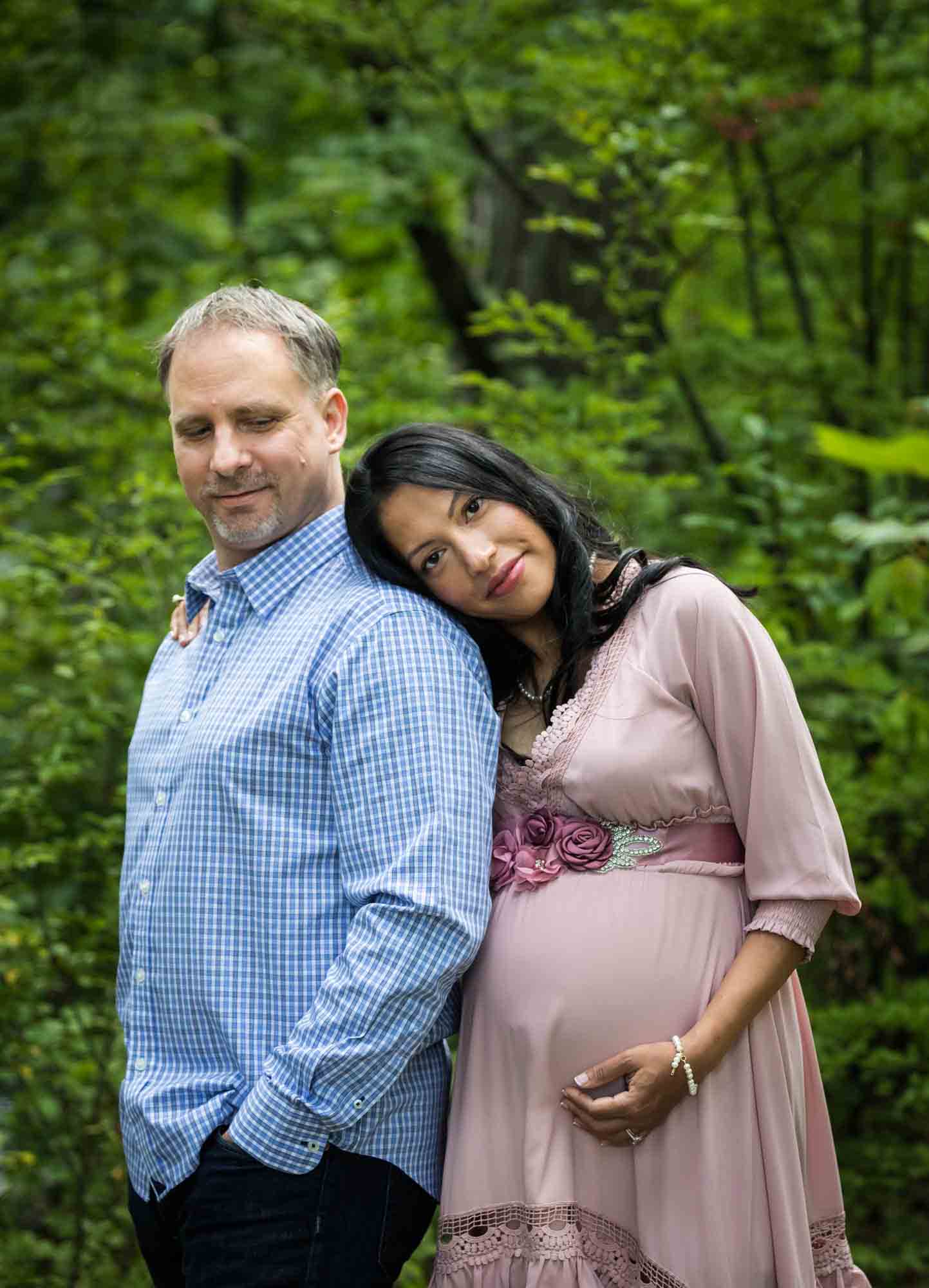 Forest Park maternity photos of a couple standing in a forest with woman's head on man's shoulder