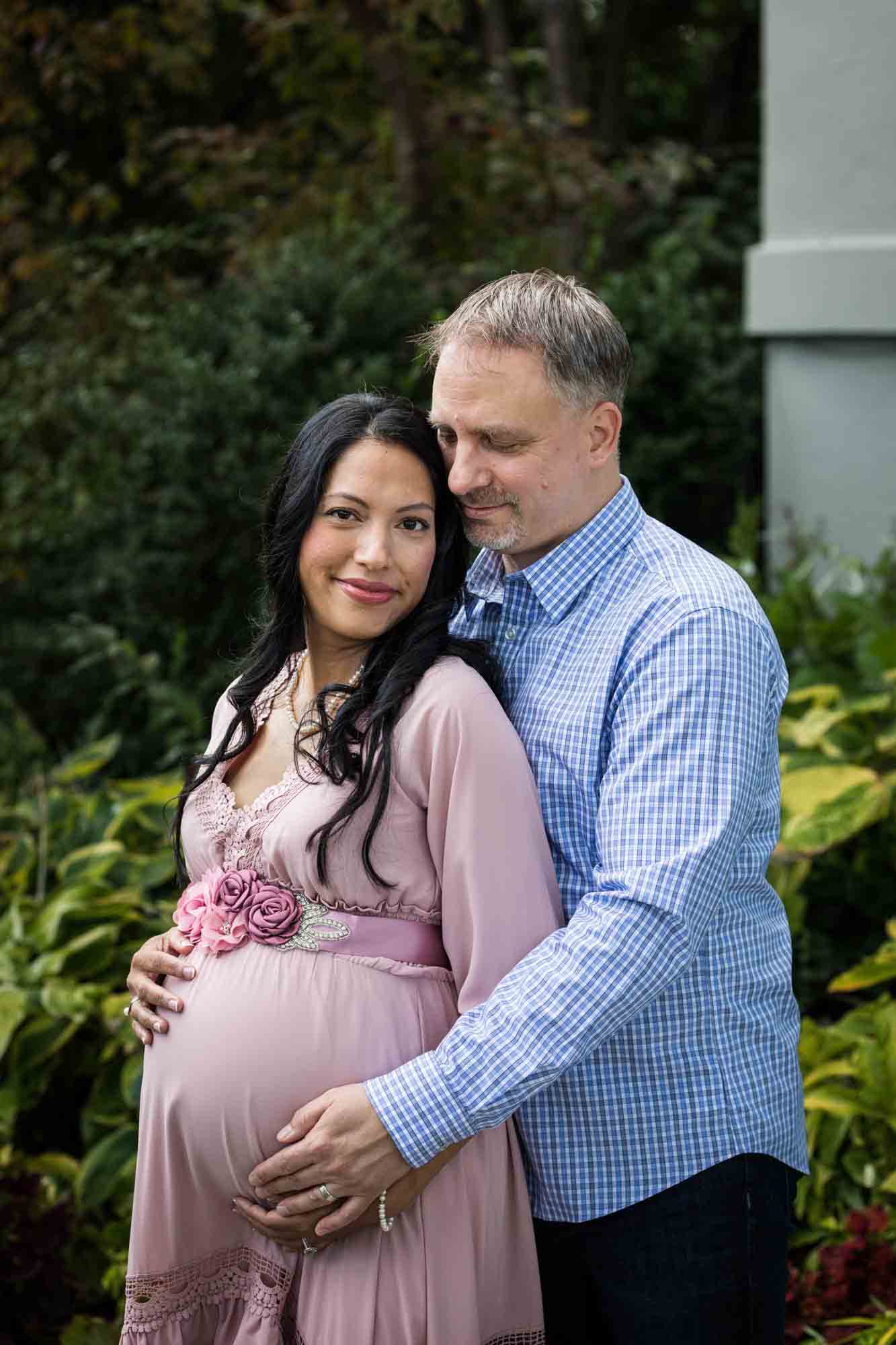 Maternity photos of couple standing in front of flowers in Forest Park