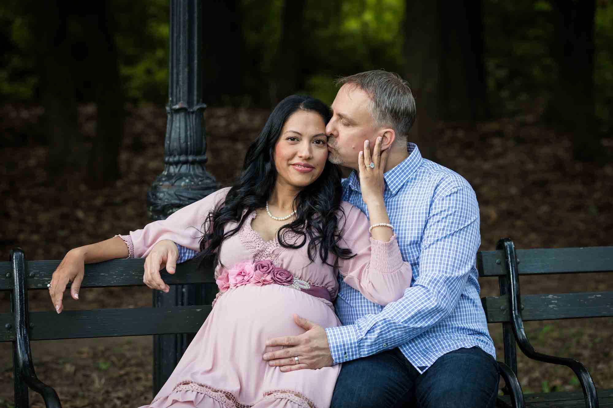 Forest Park maternity photos of couple kissing on a bench