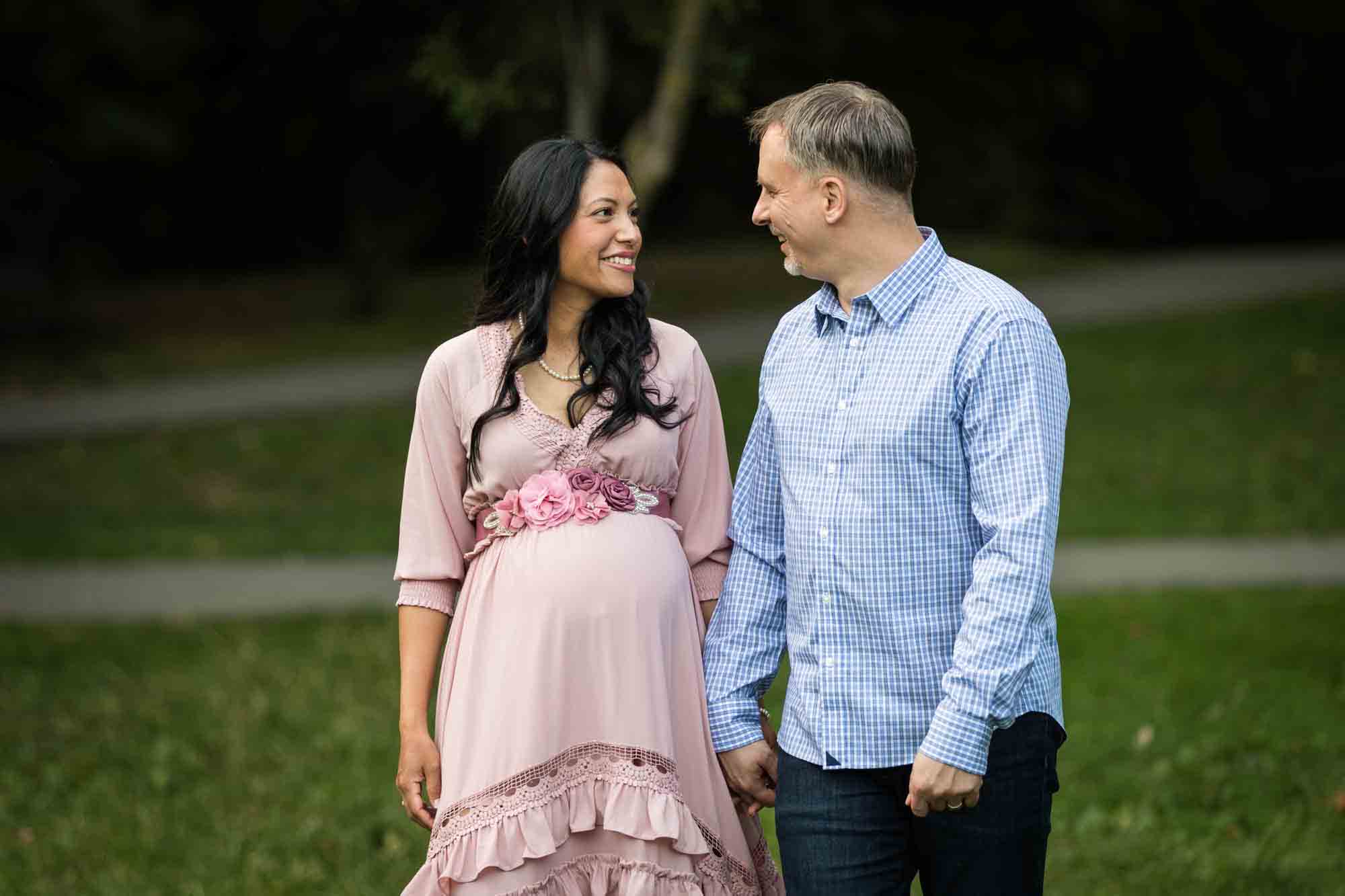 Pregnant woman and man holding hands and walking through Forest Park