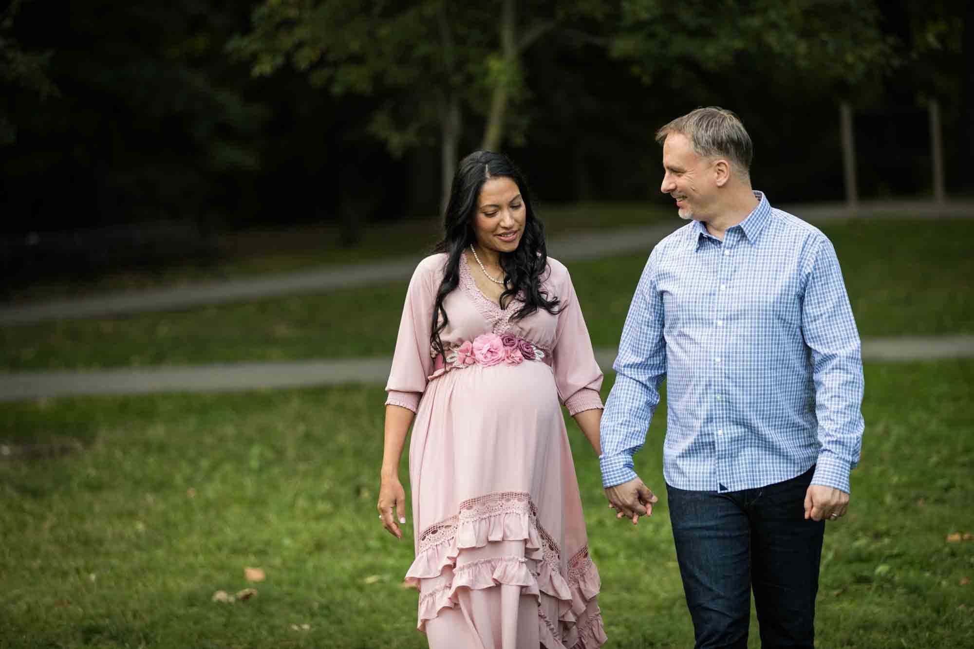 Pregnant woman and man holding hands and walking through Forest Park