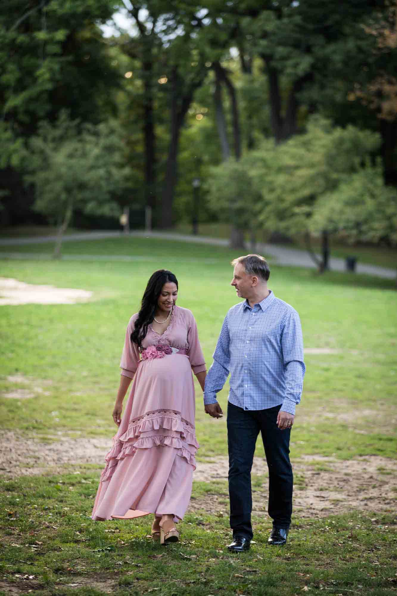 Pregnant woman and man holding hands and walking through Forest Park
