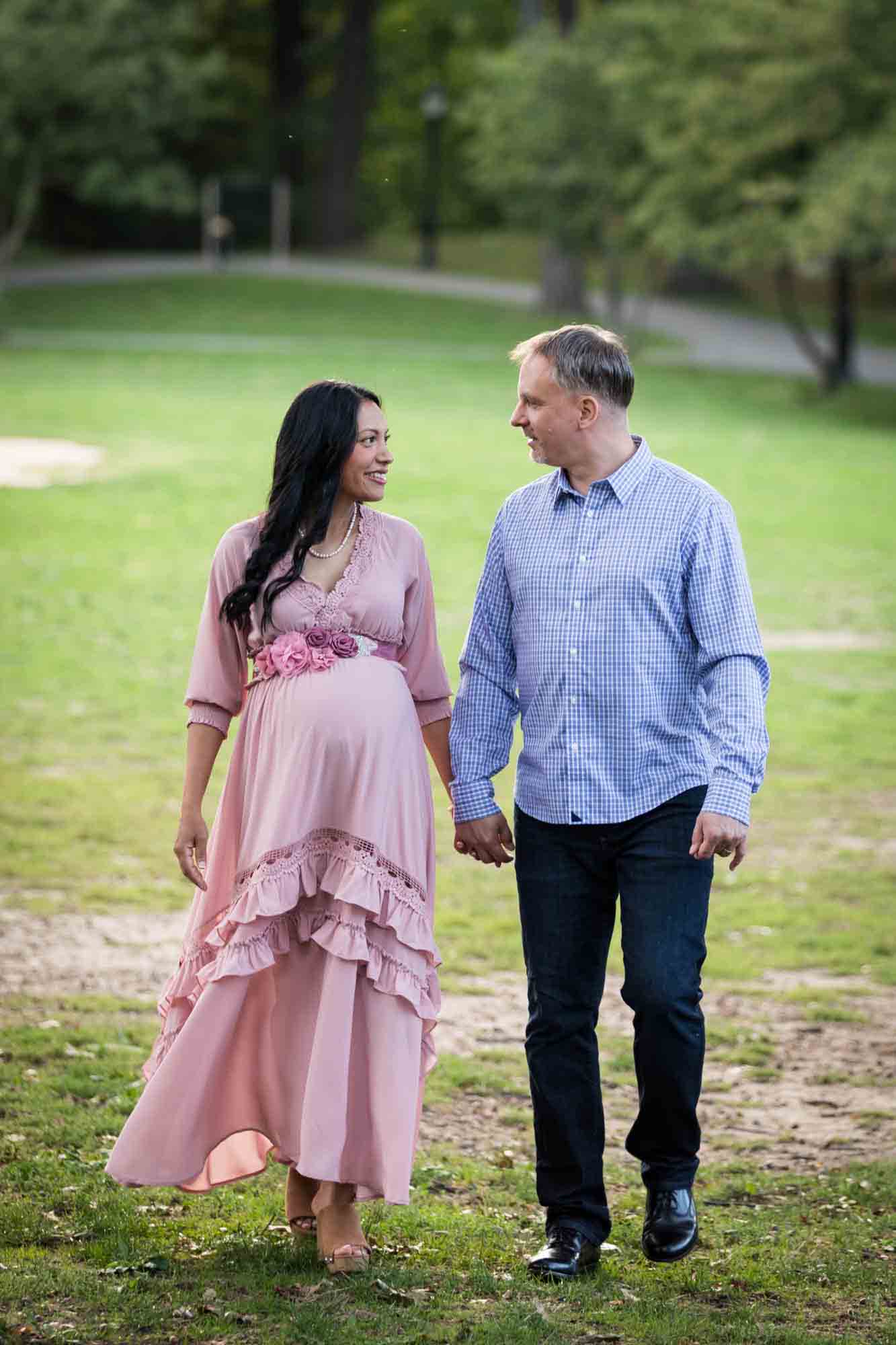 Pregnant woman and man holding hands and walking through Forest Park