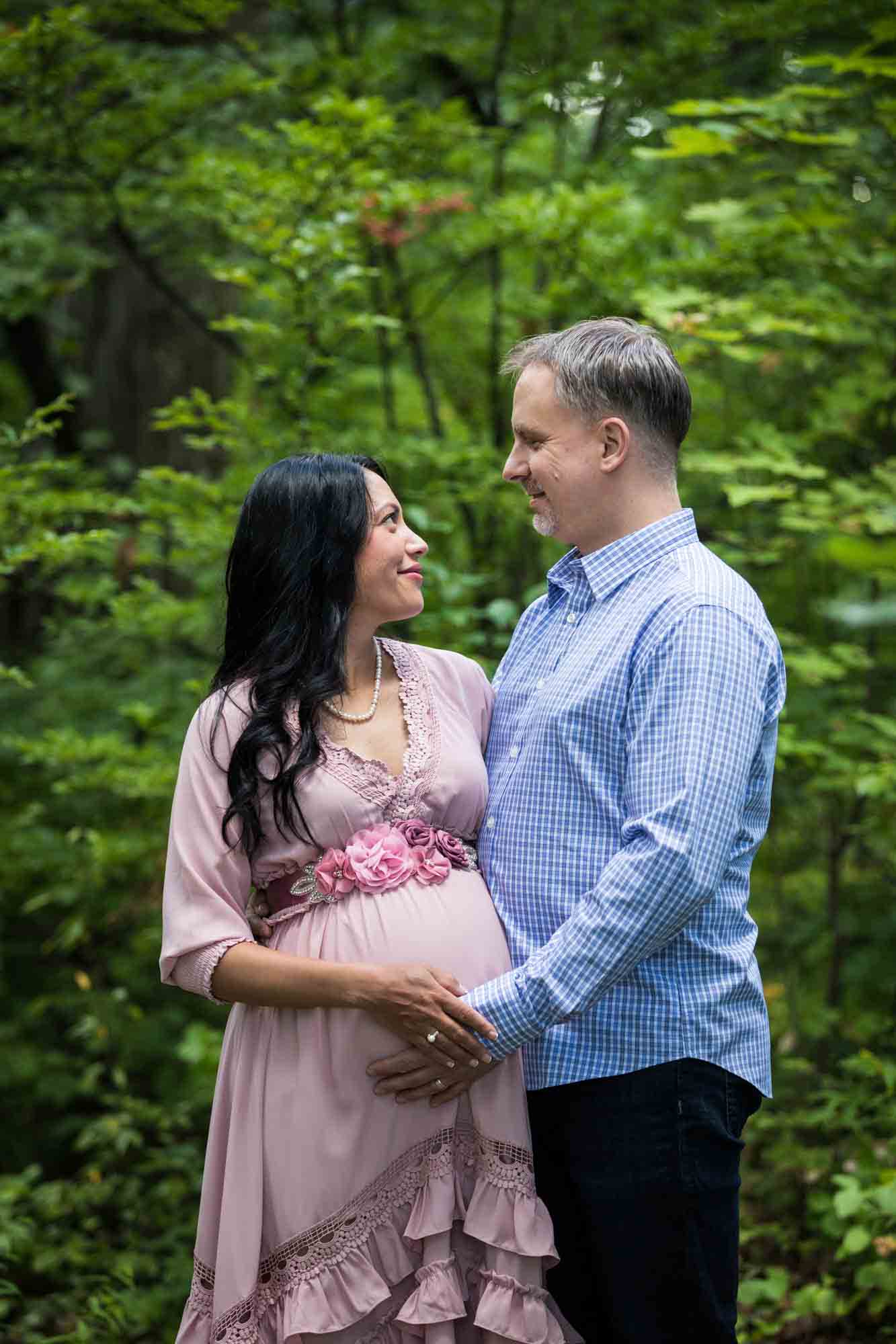 Forest Park maternity photos of a couple look at each other in a forest