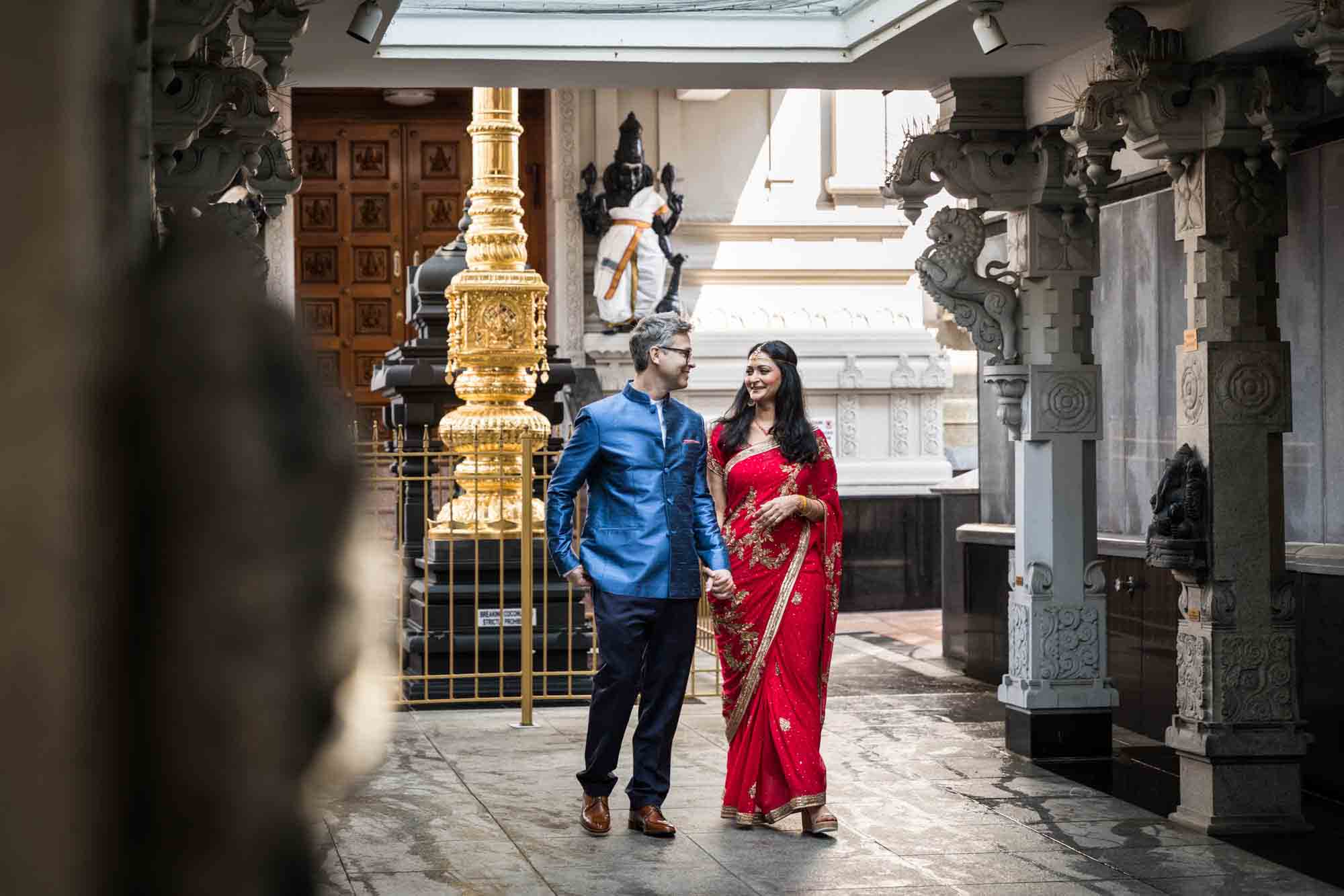 Hindu Temple Society of North America wedding photos of bride in red sari walking with groom in blue jacket