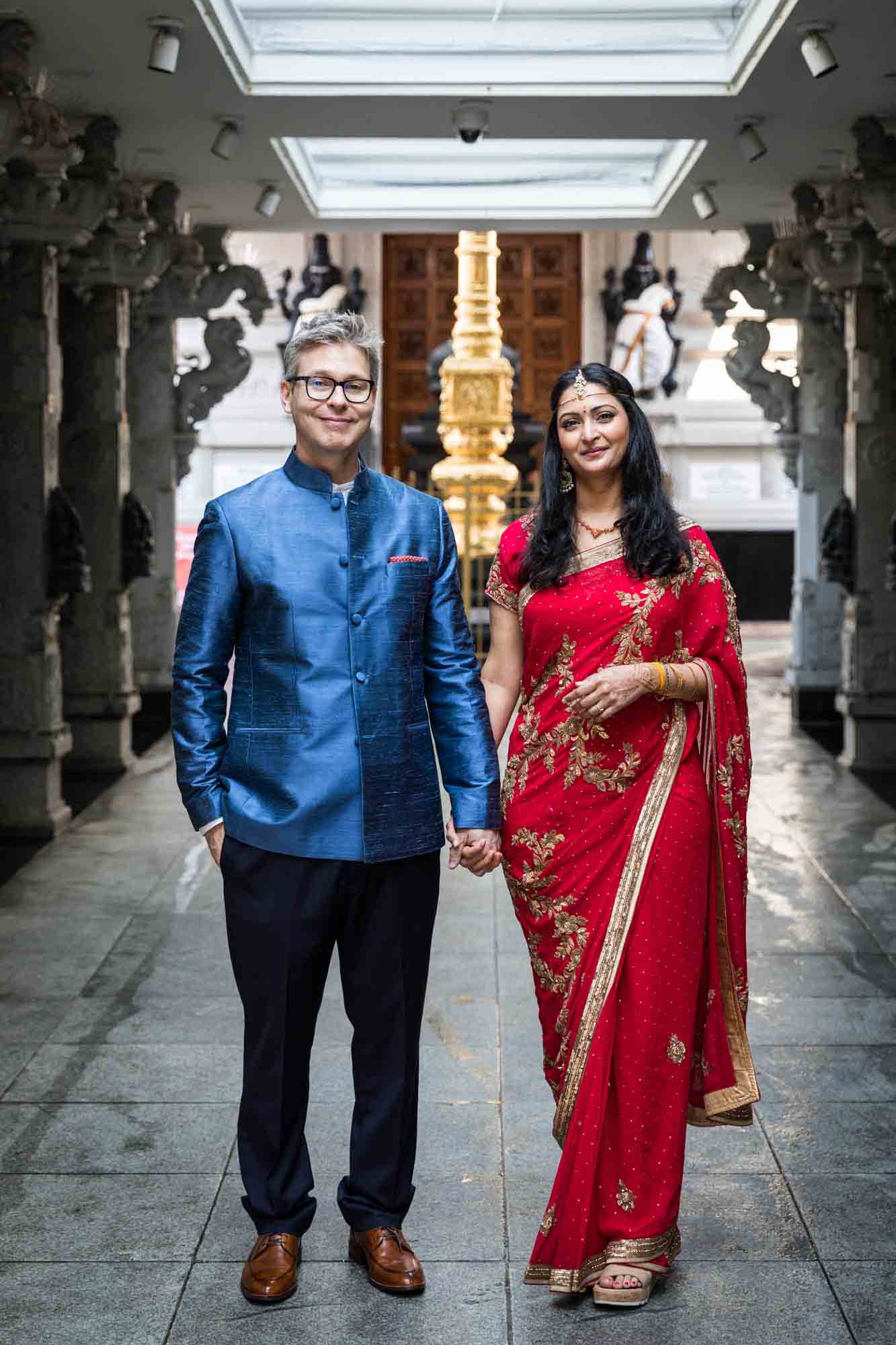 Ganesha Temple wedding photos of bride and groom holding hands in middle of main walkway
