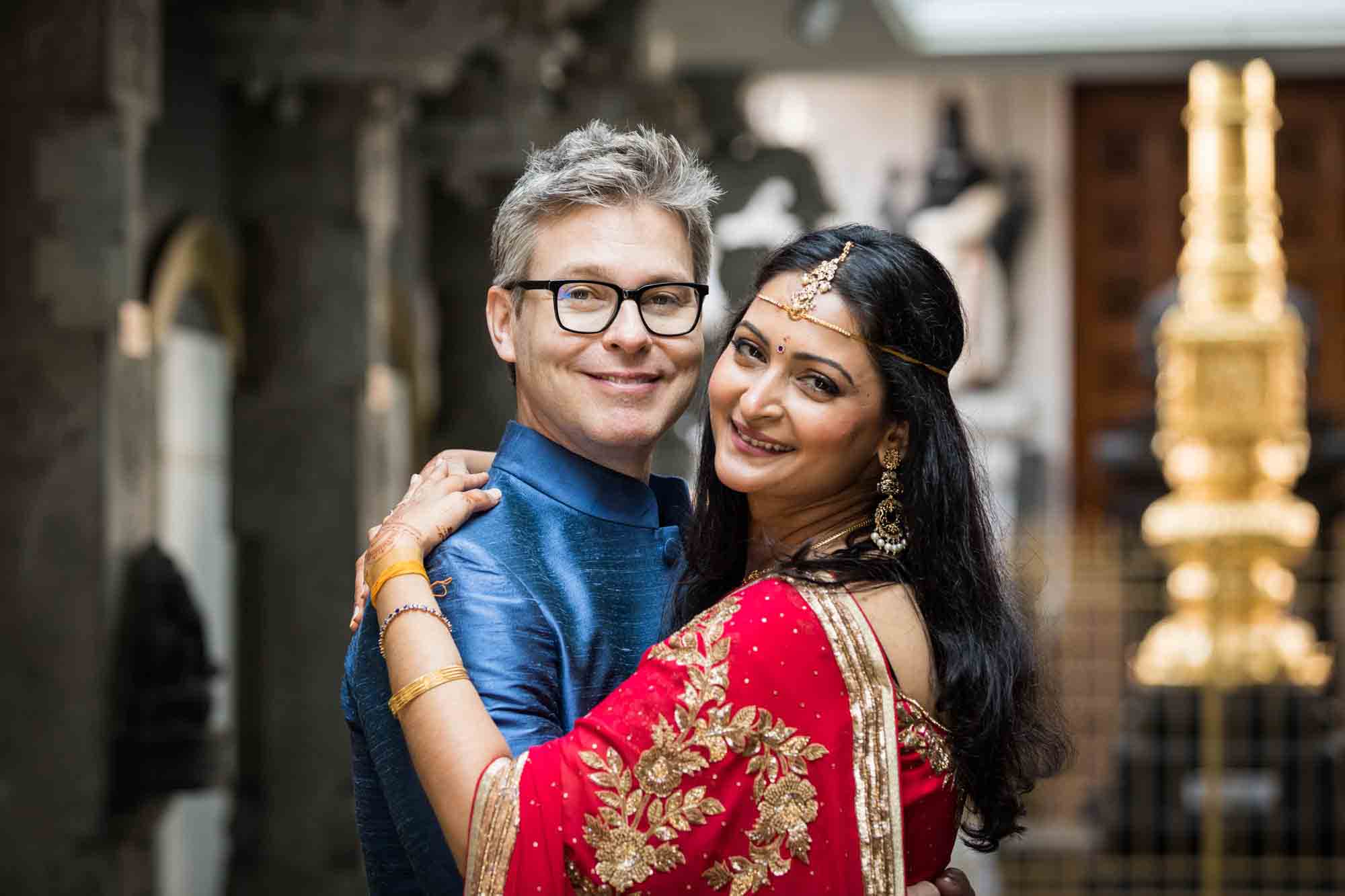 Hindu Temple Society of North America wedding photos of groom in blue shirt hugging bride in red sari