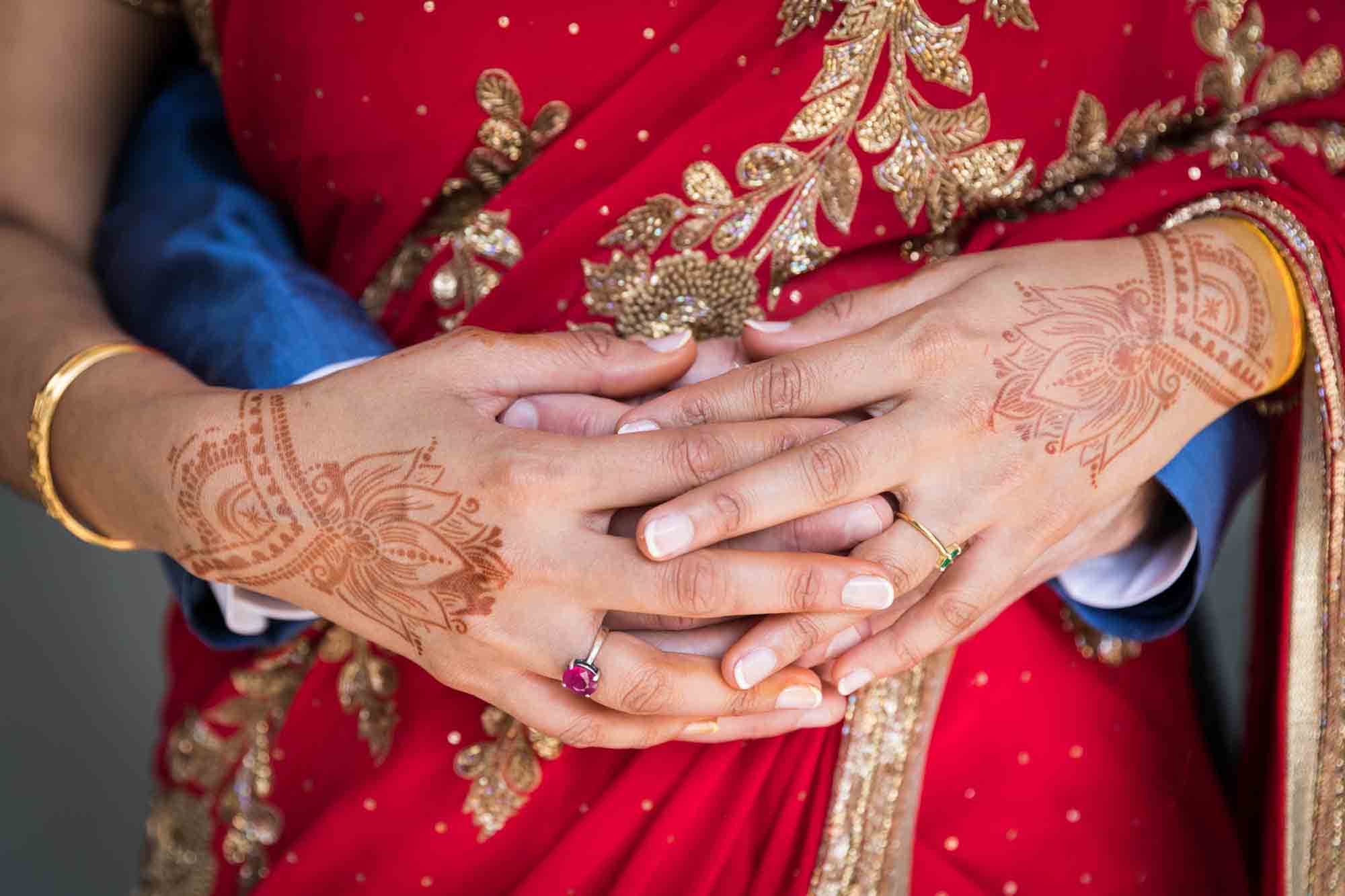 Close up of bride's hands decorated with henna holding groom's hands