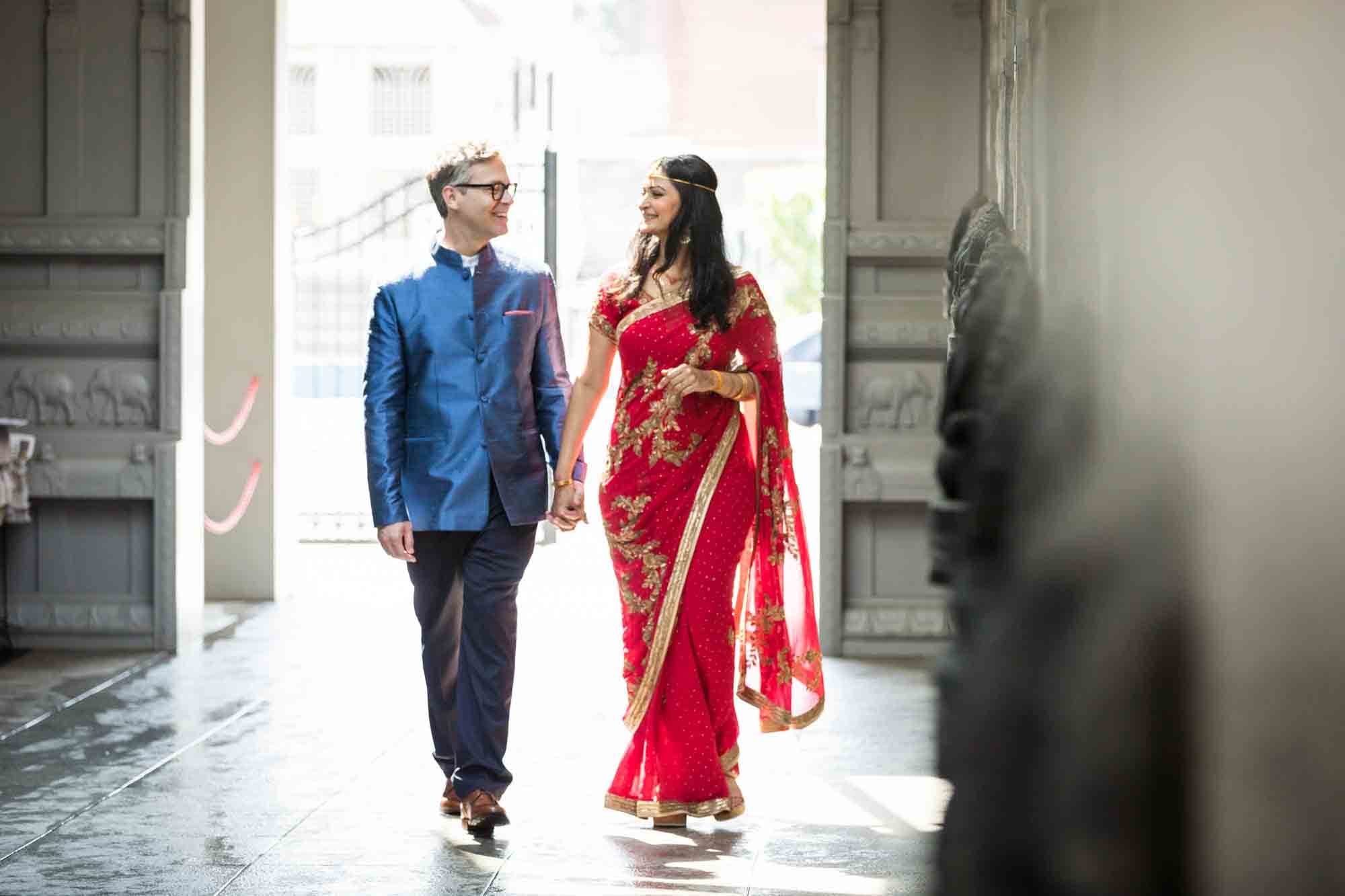 Ganesha Temple wedding photos of bride and groom holding hands and walking in main pathway