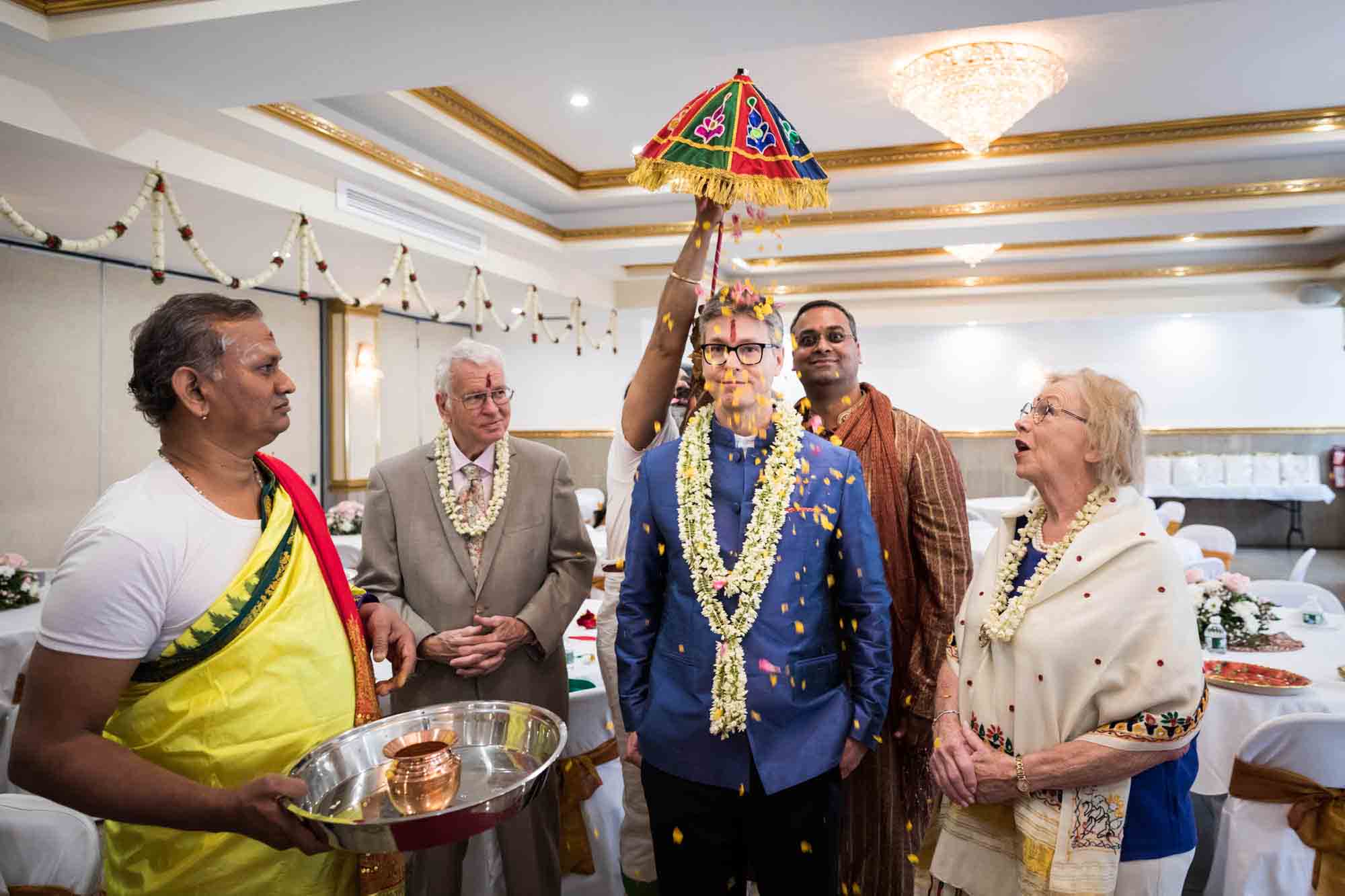 Hindu Temple Society of North America wedding photos of groom with umbrella over his head surrounded by priest and family