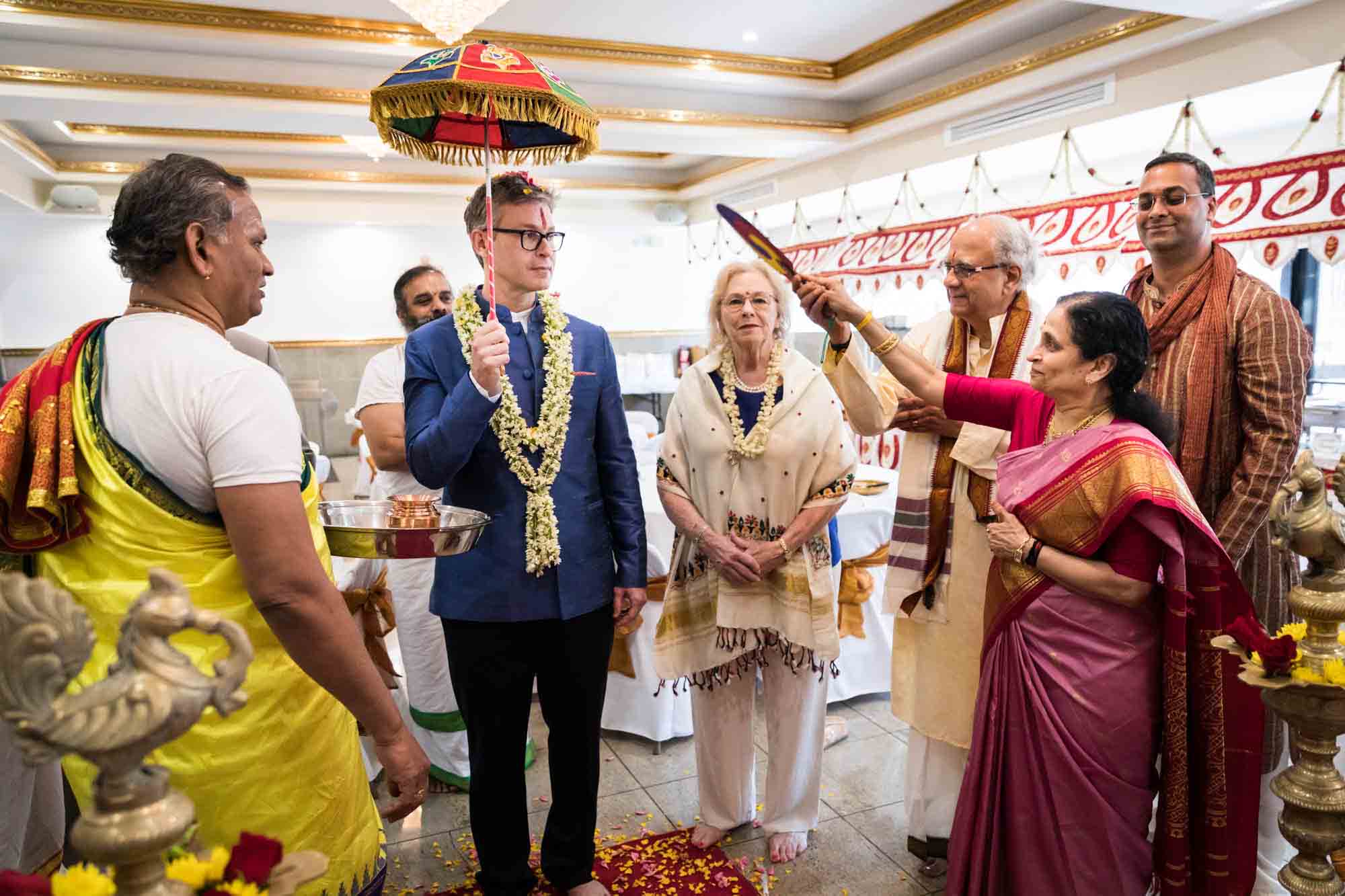 Flushing Temple wedding photos of bride's family fanning groom holding umbrella