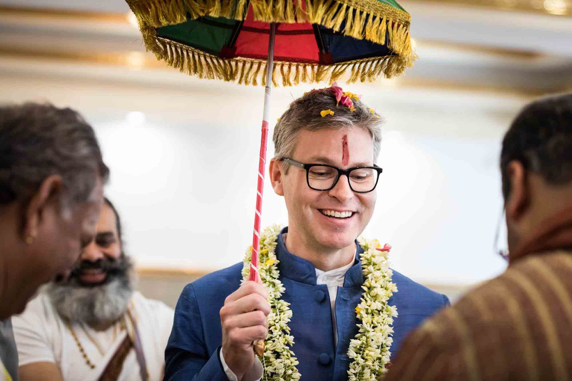 Flushing Temple wedding photos of groom holding colorful umbrella overhead
