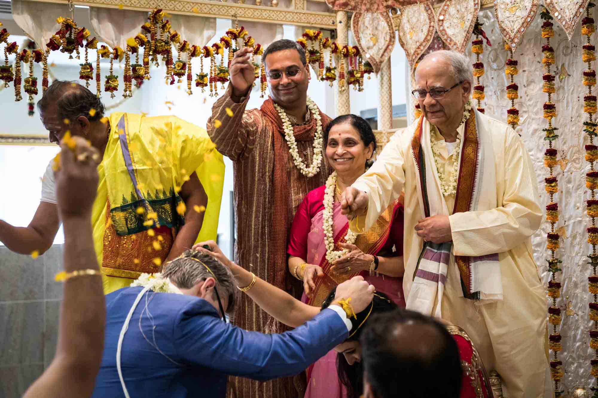 Bride's family throwing rice on bride and groom at a Hindu Temple Society of North America wedding