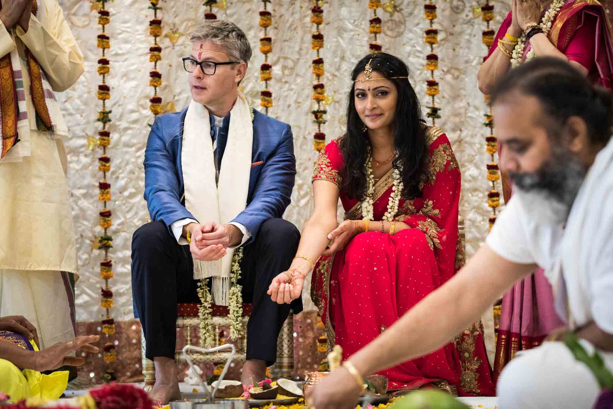 Bride and groom sitting beside each other at a Hindu Temple Society of North America wedding