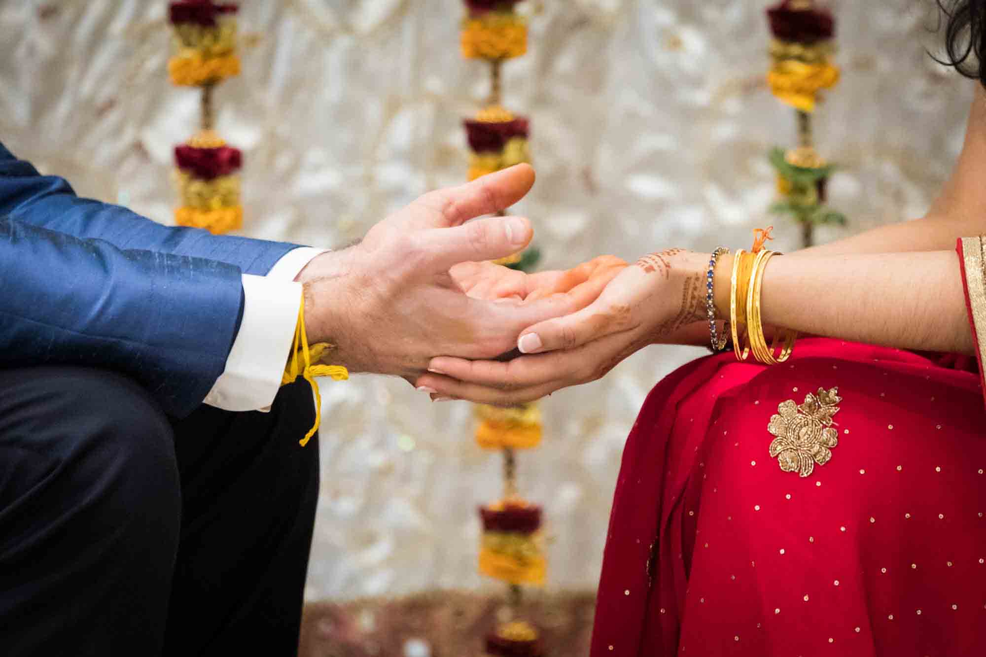 Bride holding groom's hands in front of flower garlands at a Hindu Temple Society of North America wedding