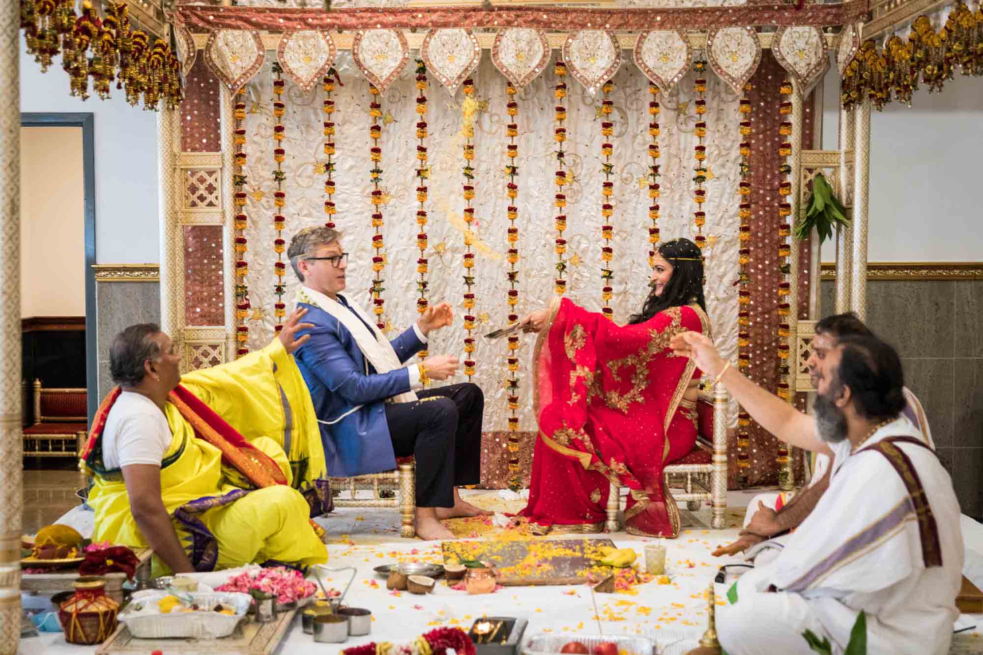 Bride and groom throwing rice at one another at a Hindu Temple Society of North America wedding
