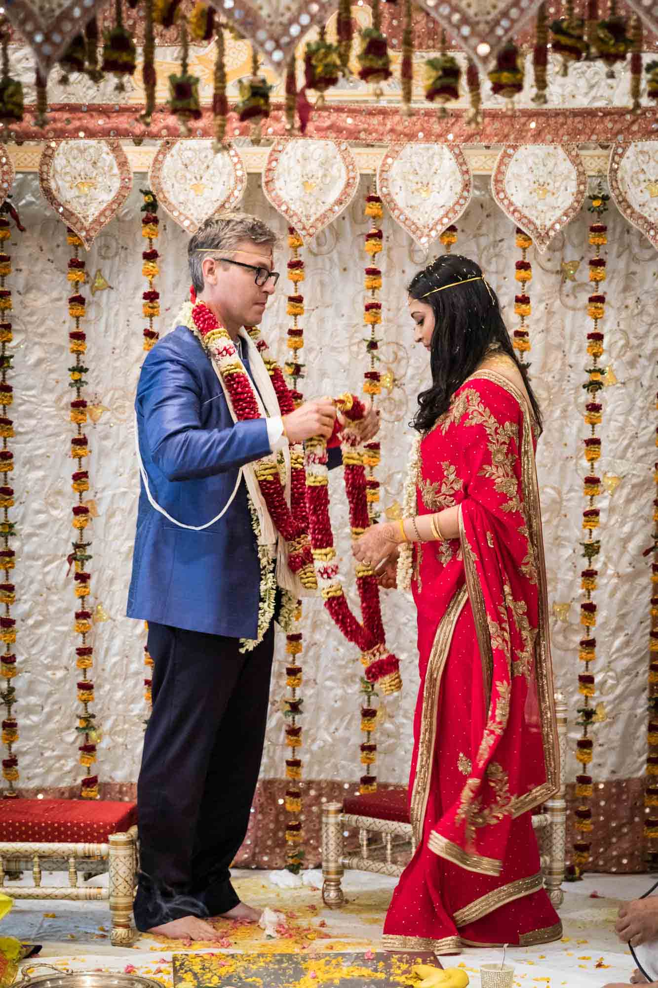 Groom putting flower garland on bride at a Hindu Temple Society of North America wedding