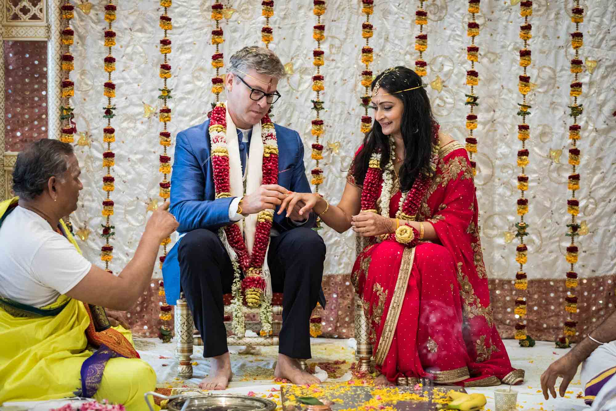 Groom putting ring on bride's hand at a Ganesha Temple wedding