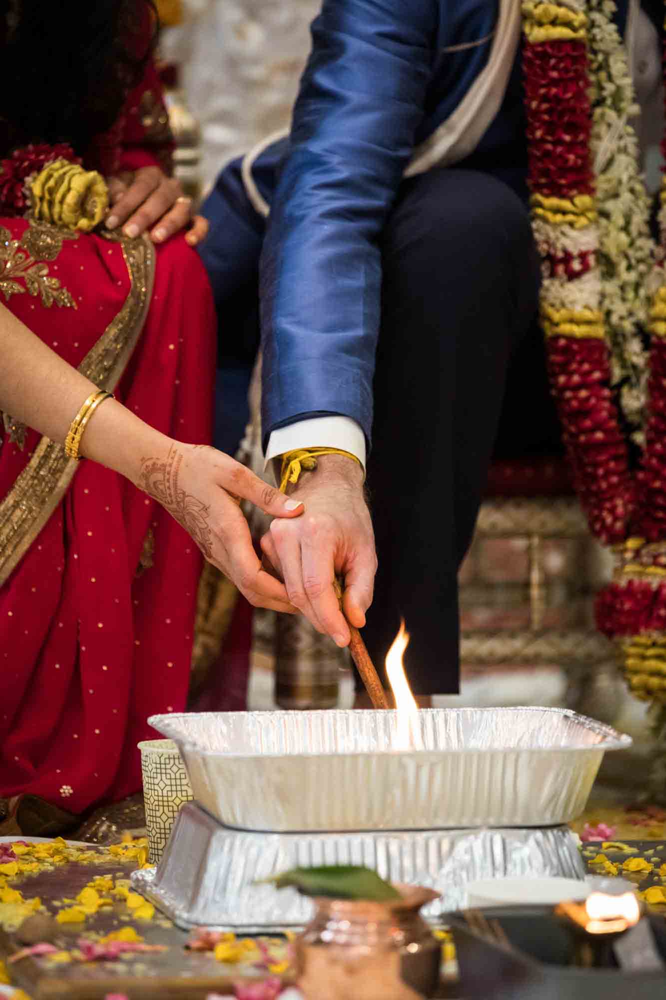 Close up of bride and groom's hands lighting fire