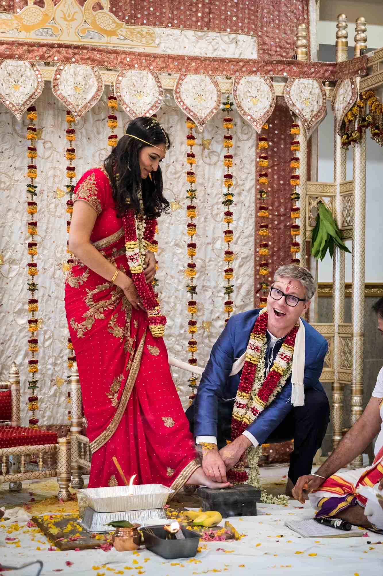 Groom putting ring on bride's toe at a Ganesha Temple wedding