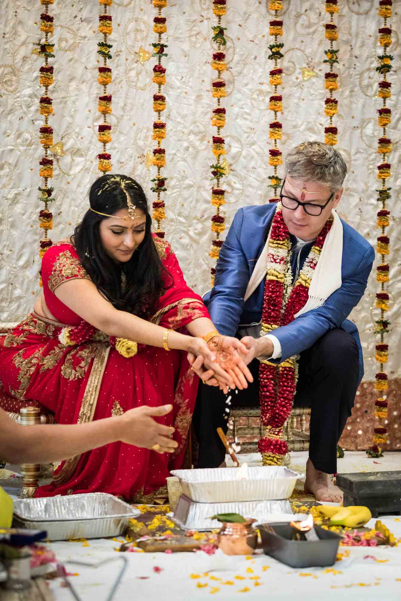 Bride and groom putting oil on fire altar at a Ganesha Temple wedding