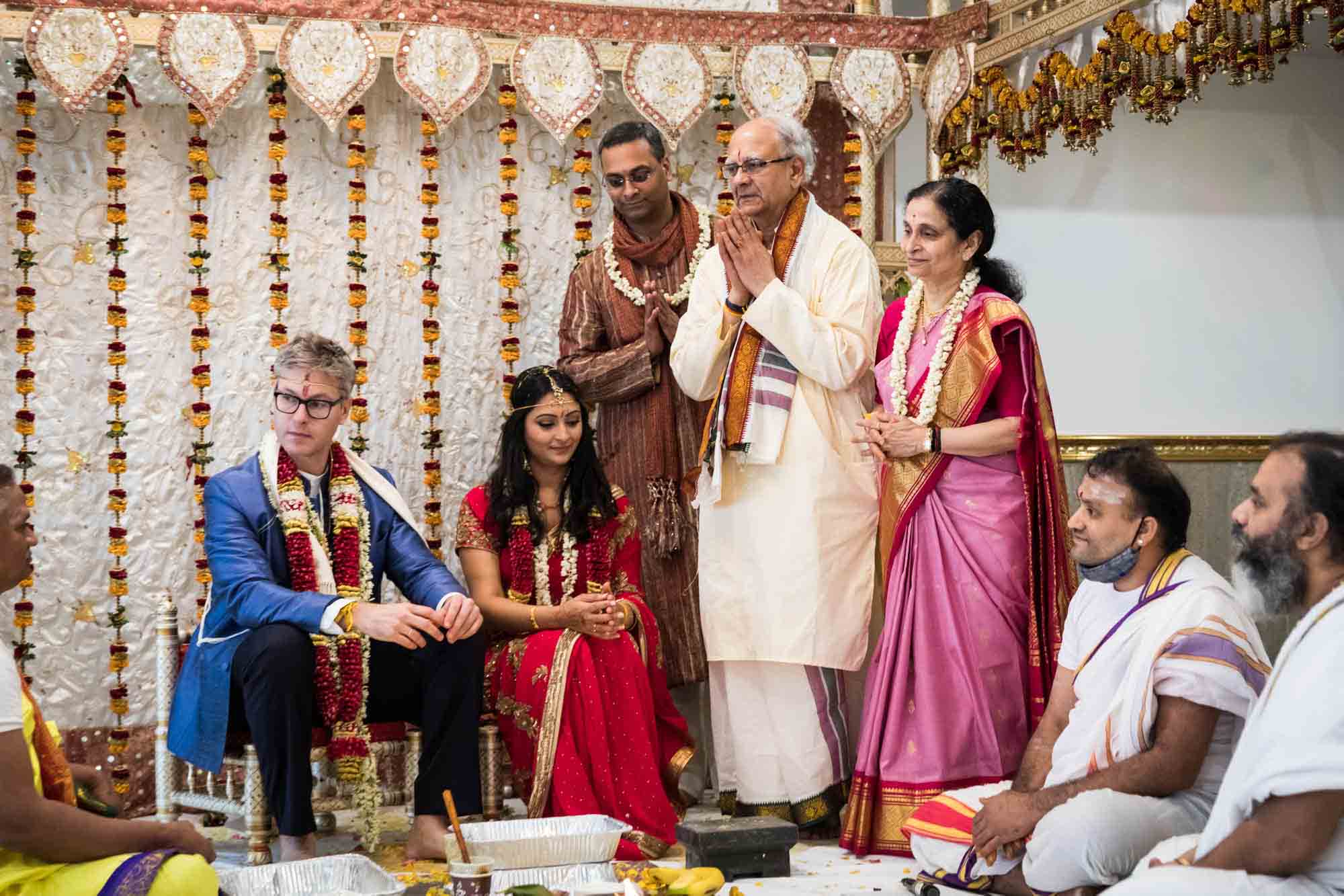 Bride and groom in front of family on stage at a Ganesha Temple wedding
