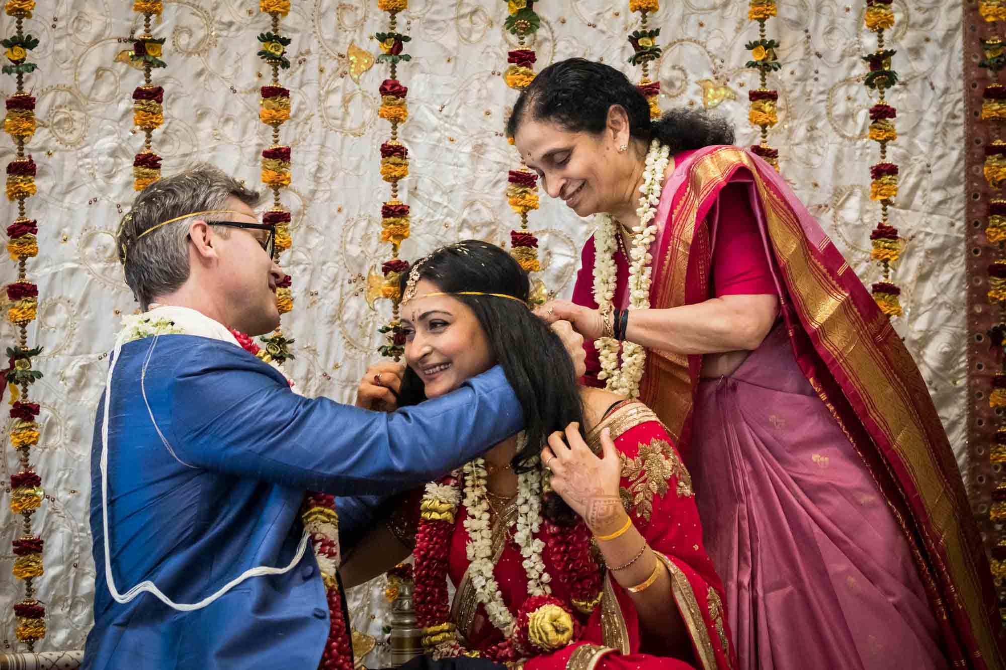 Groom and bride's mother tying necklace on bride at a Ganesha Temple wedding