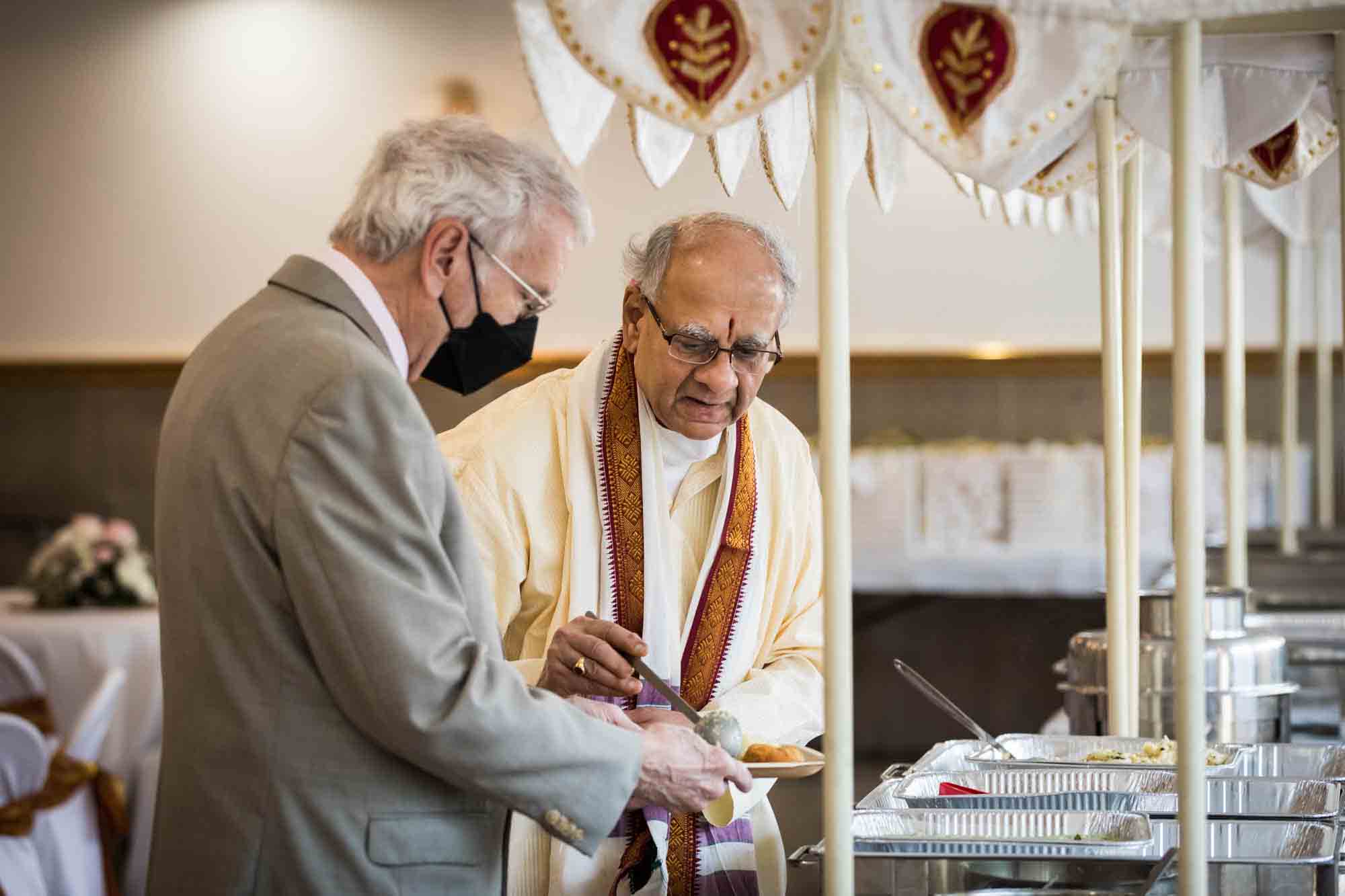Hindu Temple Society of North America wedding photos of an older man serving another older man food
