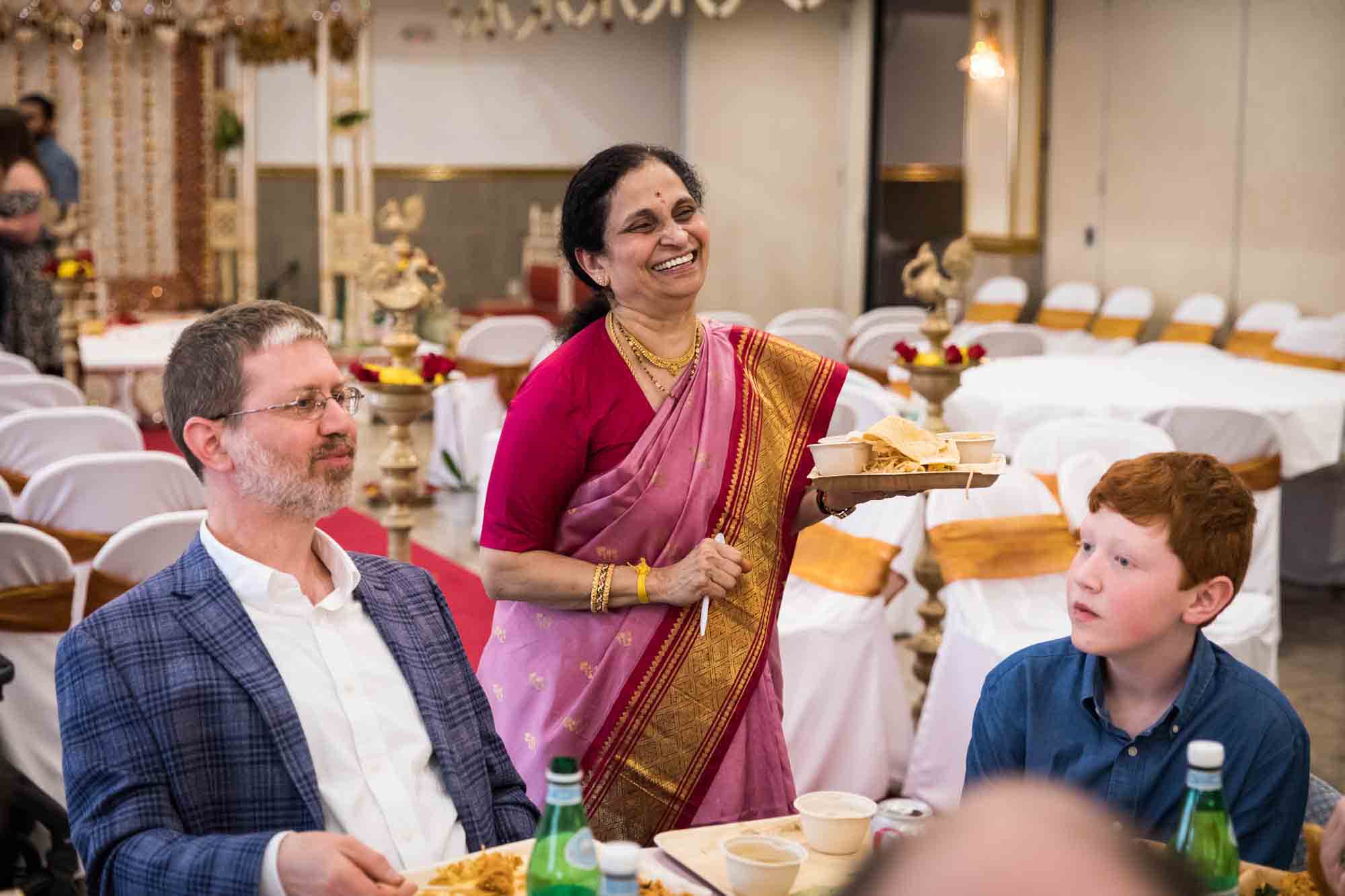 Hindu Temple Society of North America wedding photos of older Indian woman wearing sari chatting with guests at a table