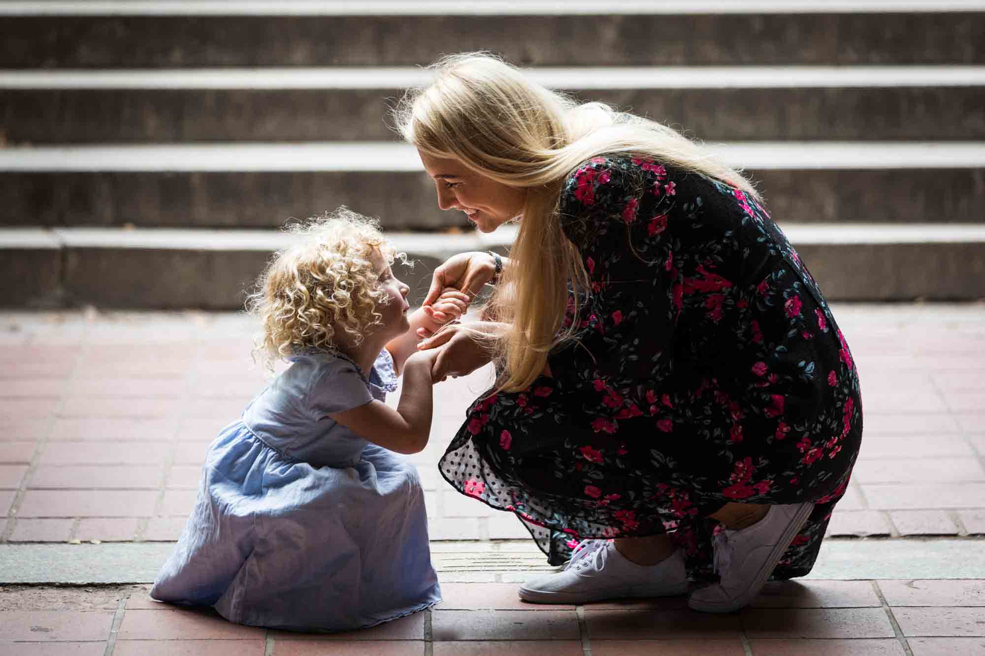 Mother and little girl crouched on ground in front of steps for an article on NYC family portrait tips for tourists