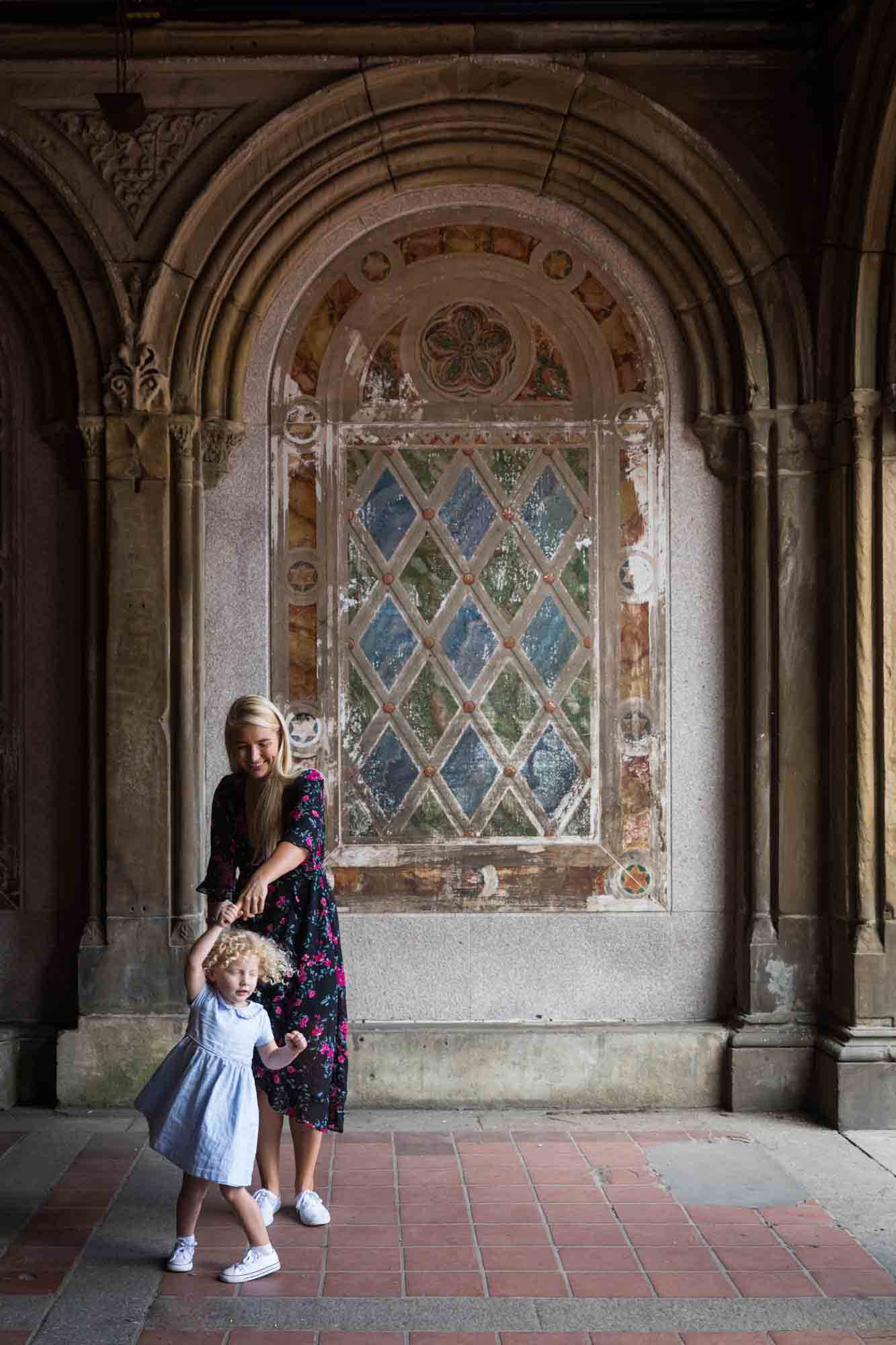 Mother and little girl dancing under Bethesda Terrace for an article on NYC family portrait tips for tourists