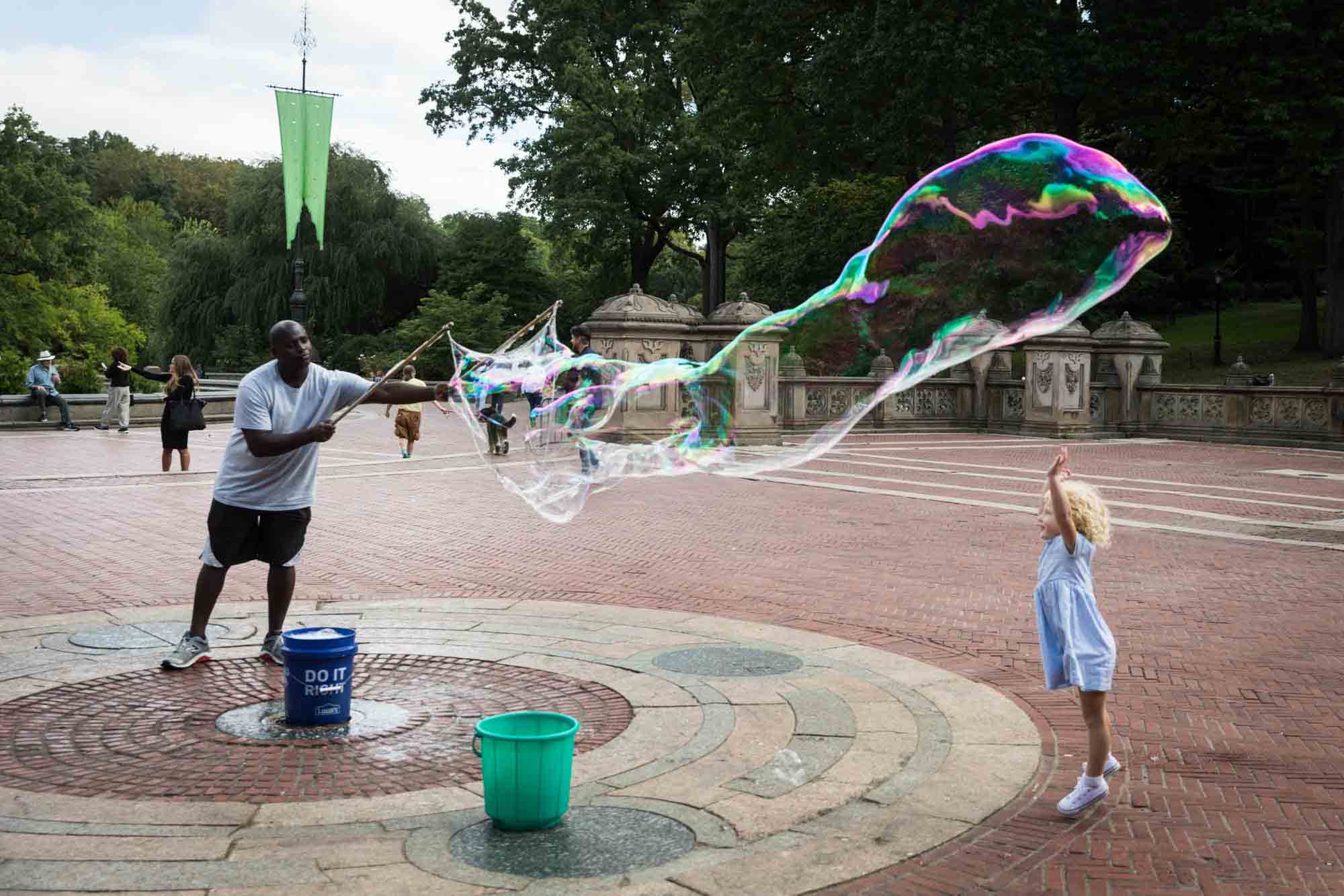 Little girl trying to touch gigantic bubble for an article on NYC family portrait tips for tourists