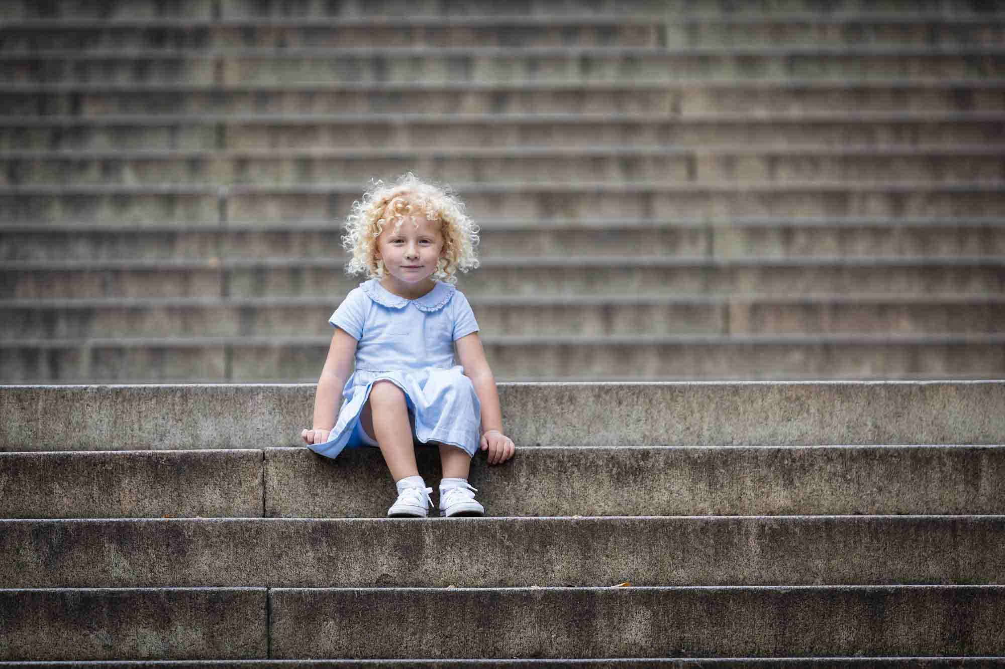 Central Park family portrait of Little blonde girl sitting on stone steps