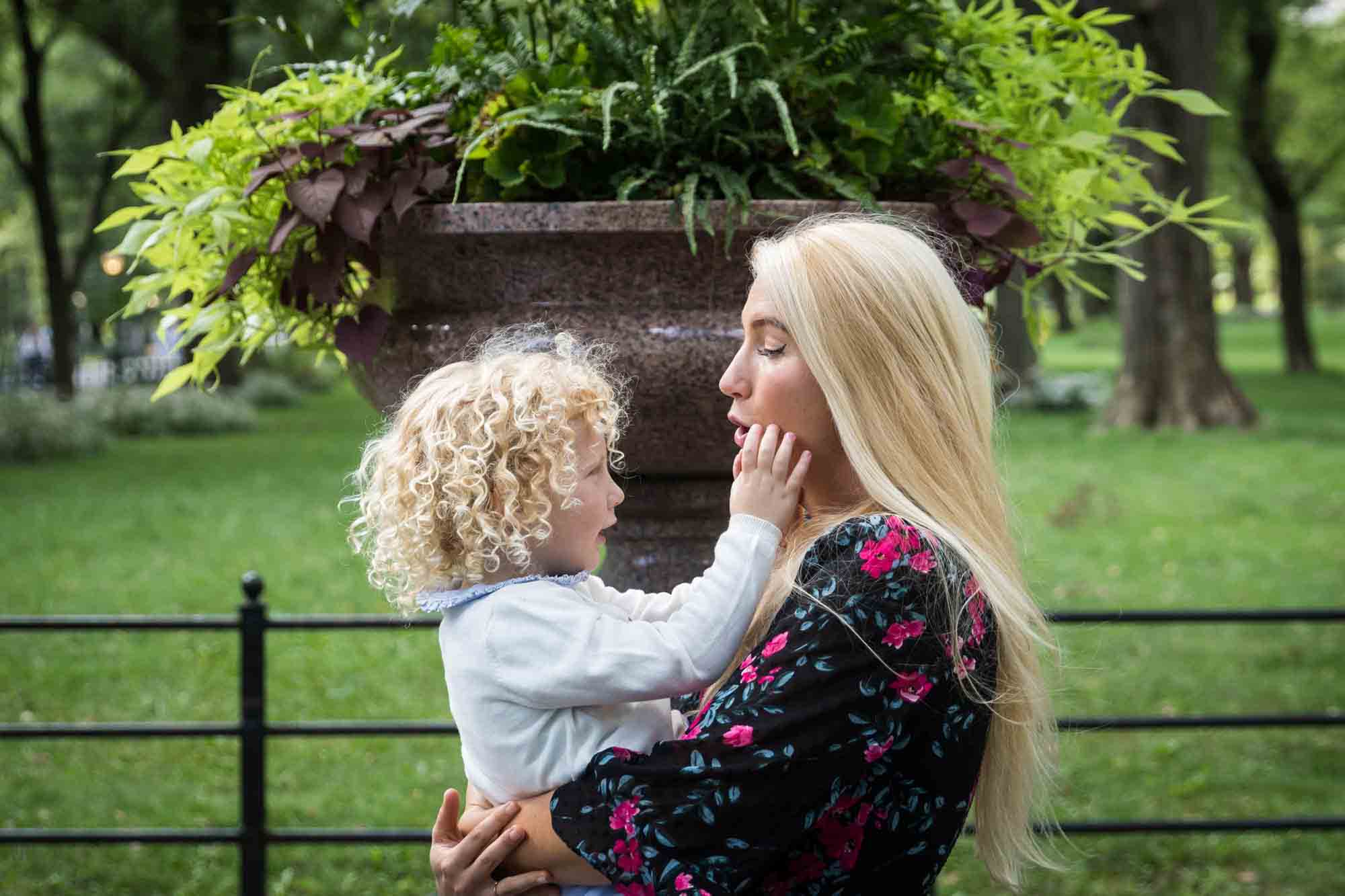 Little girl touching mother's face in front of planter for an article on NYC family portrait tips for tourists
