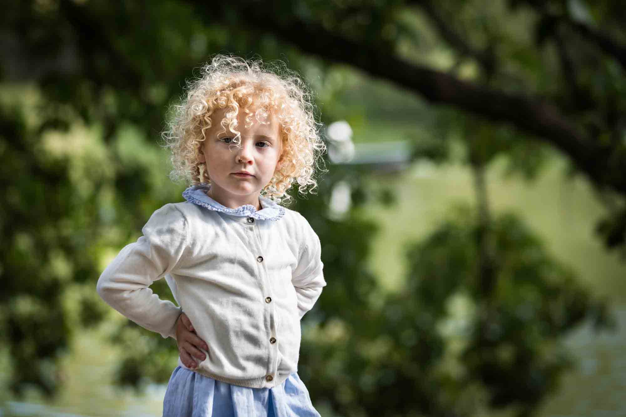 Central Park family portrait of little blonde girl with hands on hips