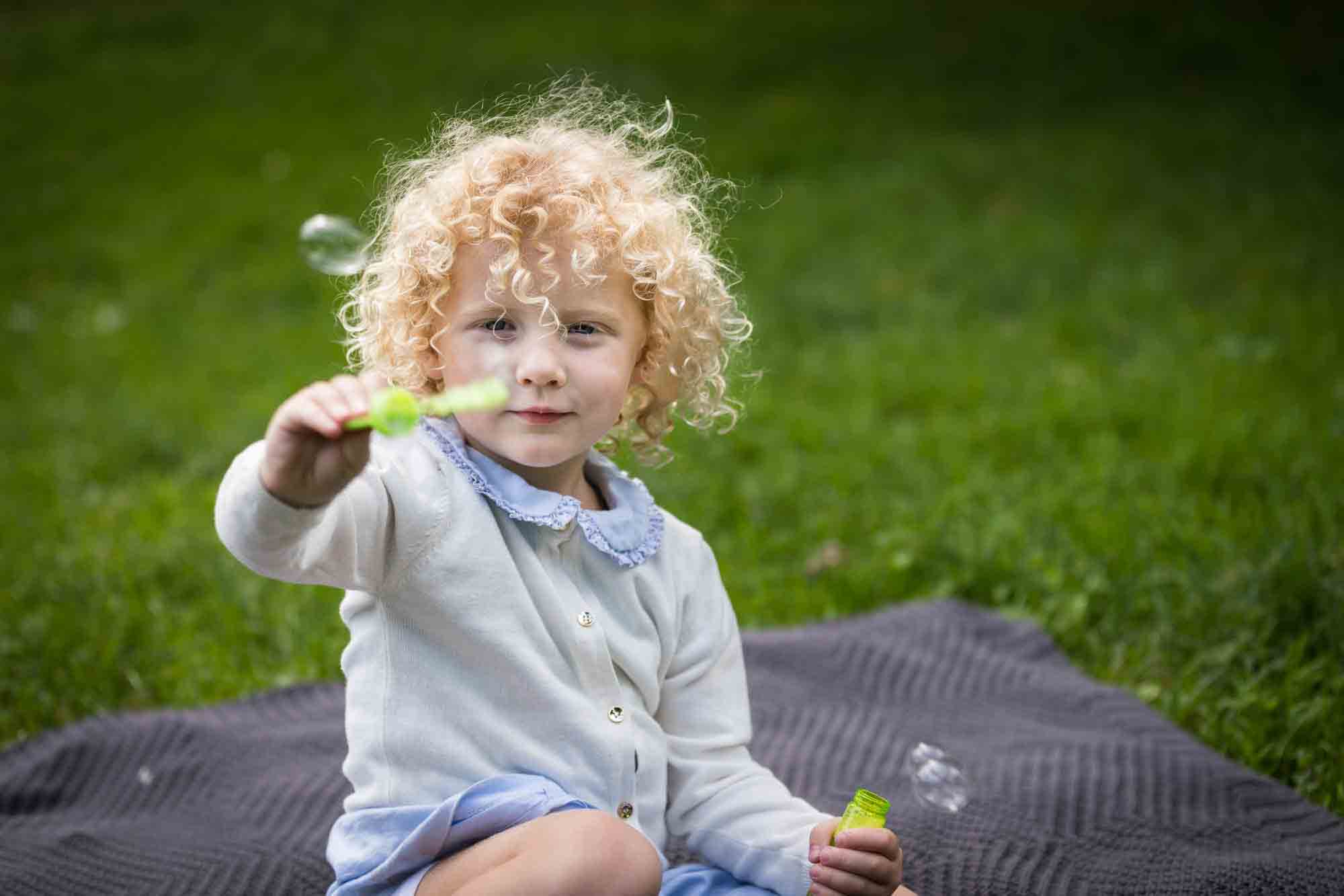 Central Park family portrait of little girl blowing bubbles